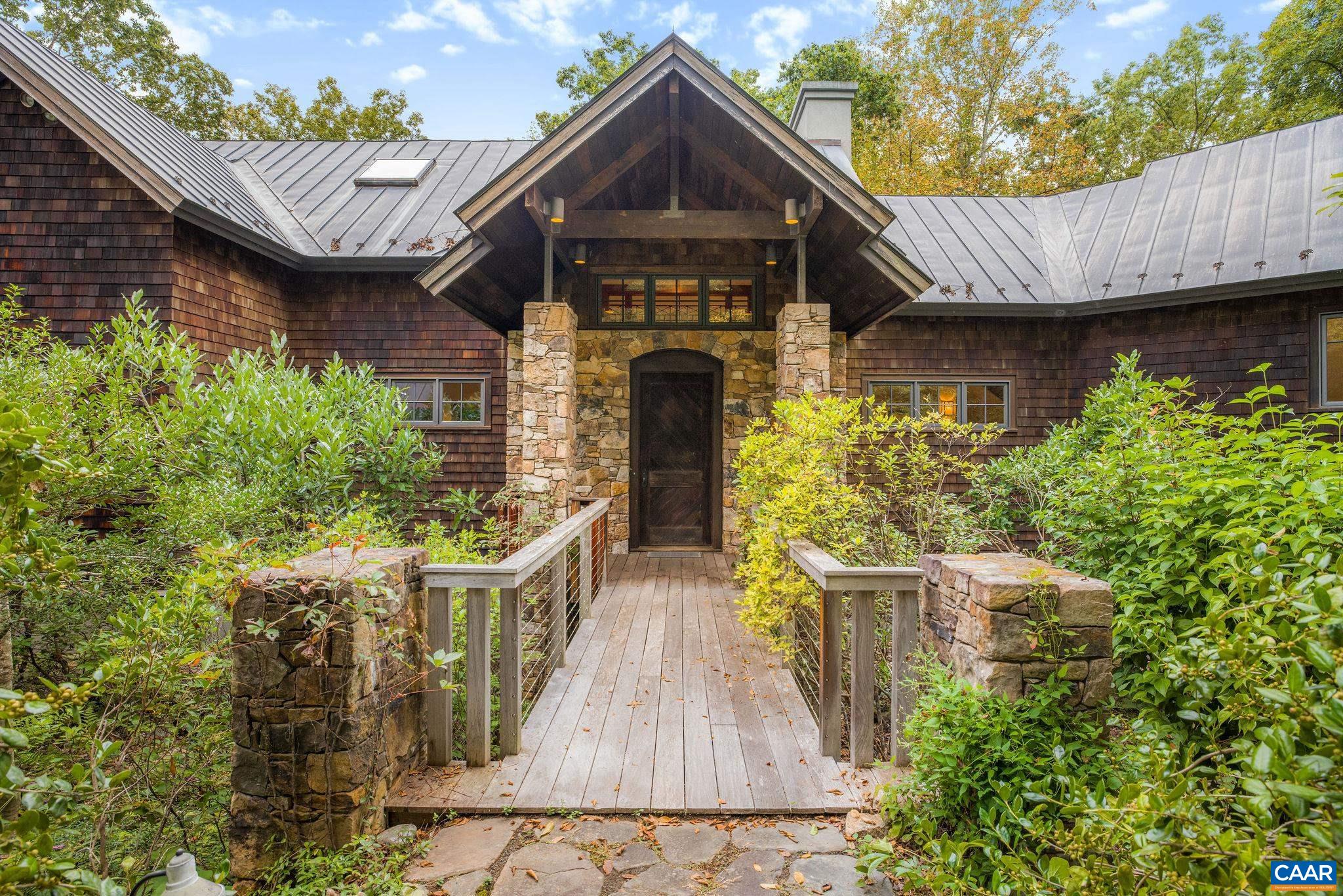 Discover this stunning architect-designed custom home, built in 1998, nestled on 21 elevated acres with views of the Rivanna Reservoir and the Blue Ridge Mountains. This exceptional property features exquisite details such as reclaimed oak and pine flooring, handcrafted heart pine cabinetry, and large glass windows that fill the space with natural light. Enjoy outdoor living on the expansive Brazilian Ipe hardwood decks or relax in the spacious screened porch. The kitchen boasts elegant soapstone countertops, while the living room showcases a dramatic 20-foot stone fireplace, perfect for cozy gatherings. With soaring ceilings and vast glass expanses, the home seamlessly blends indoor comfort with the beauty of its surroundings. Encompassed by lovely landscaping, this tranquil retreat is just three miles from Charlottesville. Amenities include a standing seam copper roof, abundant built-ins, and a geothermal HVAC system for energy efficiency. The property is primarily wooded and under conservation easement, ensuring low maintenance. Experience the magnificence of Tranquility Ridge—where natural beauty meets refined living!