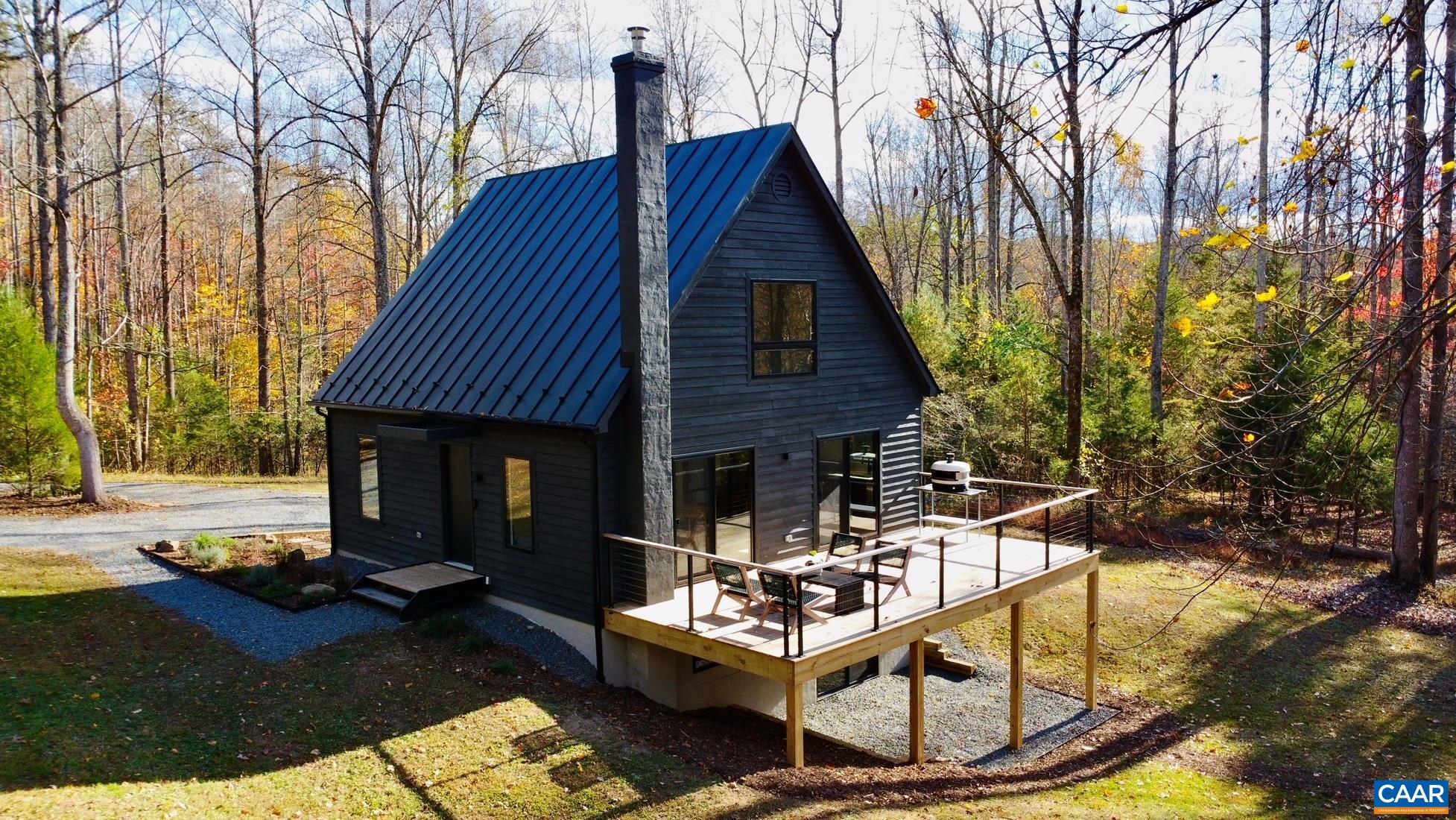 Nestled on over 5 acres of serene, mostly wooded land, this stunning modern cabin offers the perfect blend of luxury and nature. Fully renovated in 2024 (see list of improvements) with contemporary finishes and smart home technology, including high-speed fiber optic internet, the property provides a peaceful retreat with modern comforts, conveniently close to Charlottesville and the University of Virginia. This home features 3 bedrooms and 2.5 bathrooms, including a primary suite located on the main floor with an en-suite bath. Upstairs, 2 additional bedrooms with vaulted ceilings share a full bath, which includes a soaking tub, limestone flooring, and a picture window that lets in beautiful natural light. The open-concept kitchen and dining area boasts stunning quartzite and soapstone countertops. The spacious terrace-level living area, with a wood-fired stove on a custom soapstone hearth, creates the perfect spot to unwind on chilly evenings. Outside, the expansive deck offers breathtaking views, while private pathways lead to Buck Mountain Creek. Whether you are seeking a full-time residence or a weekend retreat, this home offers everything you need for comfort and relaxation.