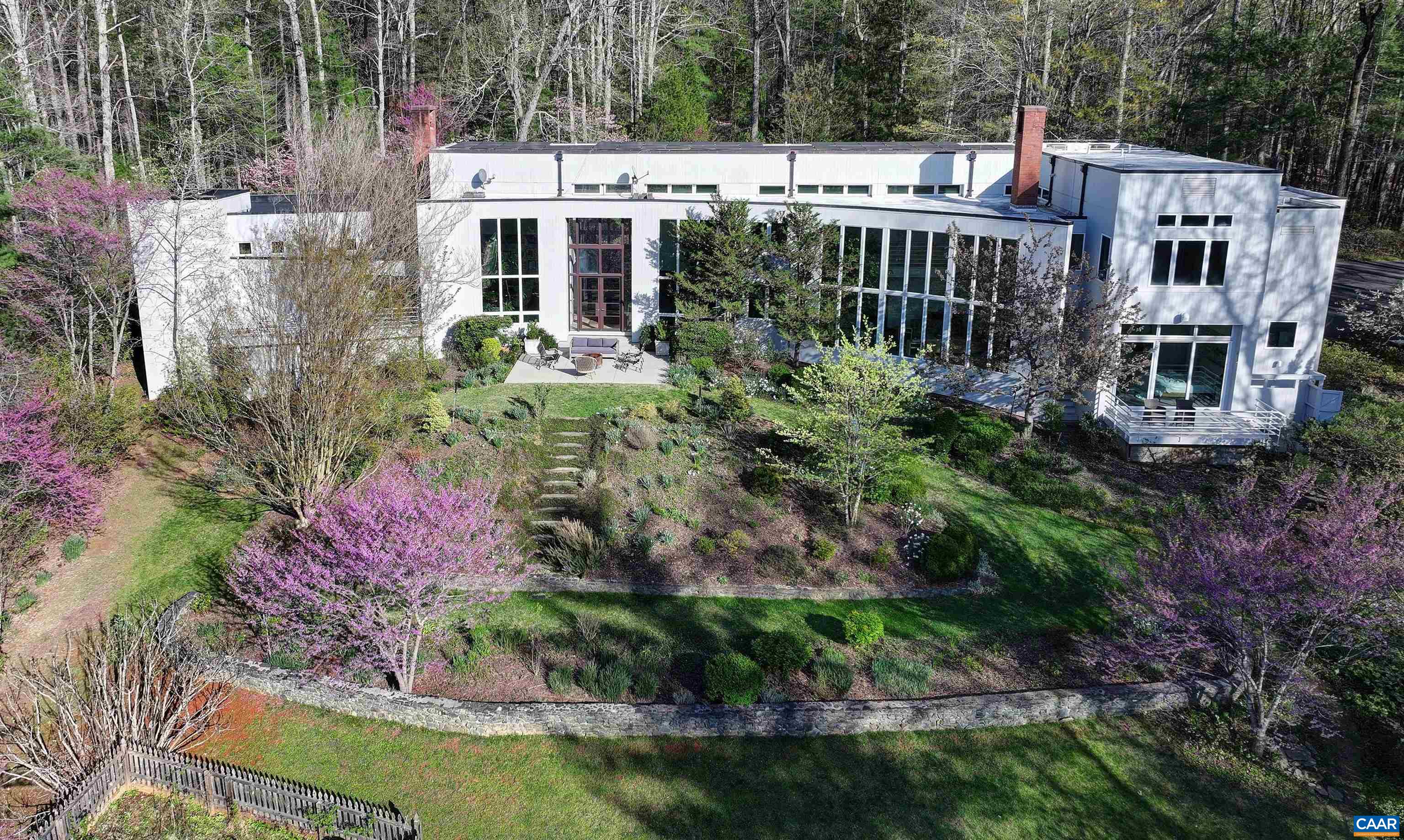 MECHUM BANKS DRIVE - Spectacular year round Blue Ridge Mountain views from this premier property in Ivy. The architecturally designed residence, masterfully showcases the breathtaking views from many rooms inviting the outdoors inside and providing awesome natural light. Spanning 6,690 finished square feet, the main level encompasses foyer; living room w/ fireplace; eat-in kitchen with high end appliances adjacent to family room w/ fireplace; spacious game room; main primary suite; mudroom; laundry & two car garage complete with chargers. Upstairs is a second primary suite, three bedrooms and two full baths. Throughout are indoor gardens, desk areas and tucked away storage. Current owners have meticulously maintained the property along with many upgrades such as solar panels, custom energy efficient shades with remote control and generator. Each season brings with it a new light and ambience. Situated on 8 acres fronting on the Mechums River, mature gardens and shrubs accent the natural setting along with a tennis court. It is truly unique to be able to retreat to such an extraordinarily tranquil home only minutes west from the activity and  amenities offered by University of Virginia and Charlottesville.