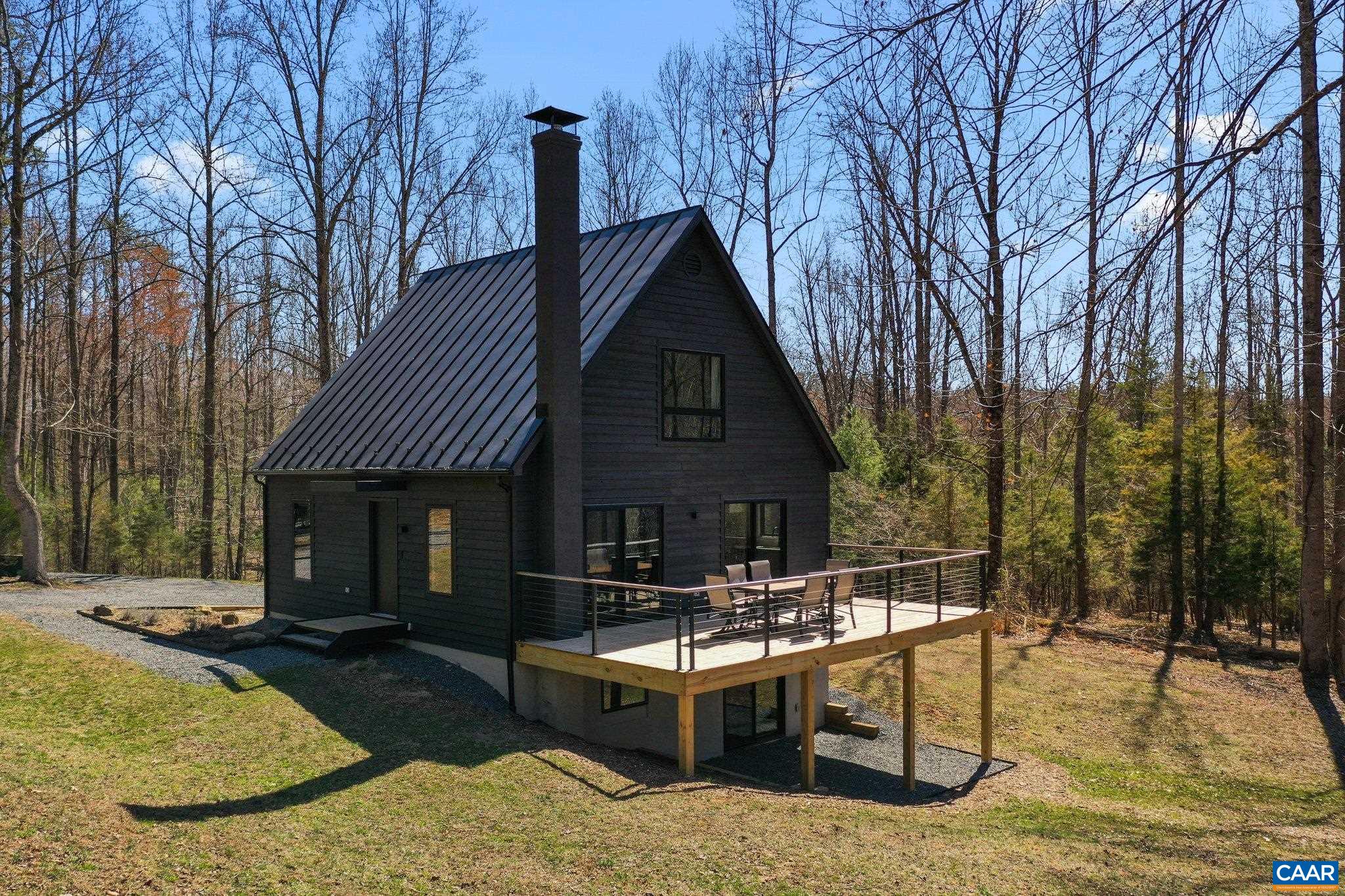 Tucked away on over 5 acres of mostly wooded land, this beautifully renovated, light-filled modern home blends contemporary elegance with the beauty of nature. Offering upscale custom finishes and high-speed fiber optic internet, it provides a peaceful escape while remaining conveniently close to Charlottesville and UVA. Inside, the home features three bedrooms and two and a half bathrooms, including a main-level primary suite with an en-suite bath. The upper level boasts two spacious bedrooms with vaulted ceilings, sharing a full bath complete with a soaking tub and limestone flooring. The open-concept kitchen and dining area shine with quartzite and soapstone countertops, while the terrace-level living space—anchored by a cozy wood-fired stove on a custom soapstone hearth—invites you to relax on cool evenings. Step outside to enjoy picturesque views from the expansive deck or explore private trails, leading to view of a creek, exposed boulders and rock outcroppings. Whether you’re looking for a full-time home or a weekend retreat, this stunning property offers the perfect balance of luxury, comfort, and nature.
