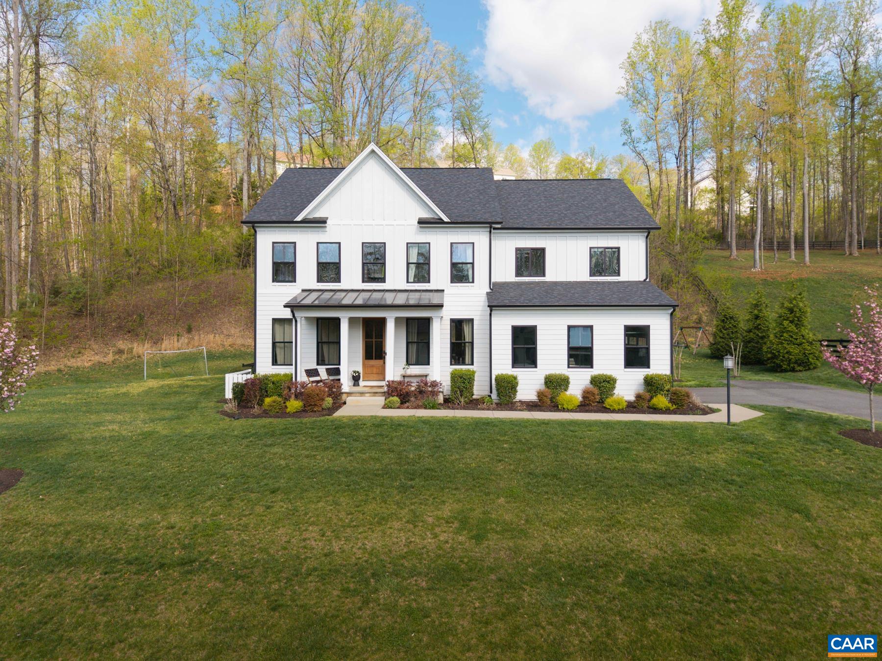Welcome to 1773 Warbler Way—where classic farmhouse charm meets clean, modern design. Located in desirable Whittington, just minutes from downtown Charlottesville, I-64, and UVA Hospital, this home blends peaceful living with everyday convenience. Sunrise views from the front porch and adjacent community woods create a connected, serene setting. Inside, the open main level centers around a modern kitchen with an expansive island, large pantry, office nook, and mudroom. The living room features a gas fireplace with rustic wood mantle and shiplap surround, while large windows let sunlight pour in. A formal dining room and dedicated office complete the main floor. A timeless palette and finishes elevate the space without feeling fussy. Upstairs, four bedrooms include a spacious primary suite with sitting area, two walk-in closets, and a bright, modern bath. The finished basement adds flexible space for relaxing, play, or workouts, plus an unfinished area ready for a fifth bedroom or studio. Neighborhood trails offer space for kids and dogs to explore.