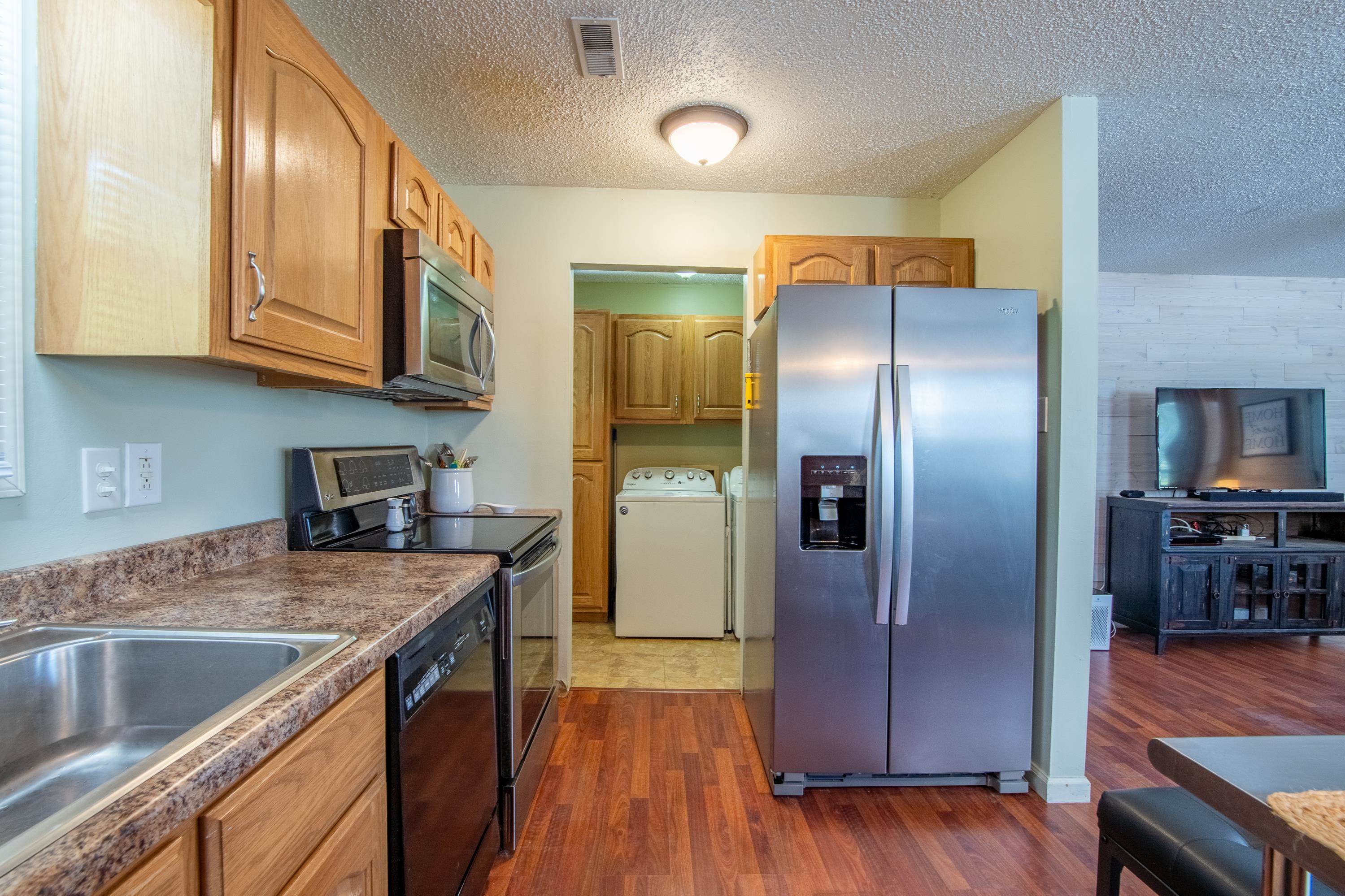 Kitchen featuring stainless steel appliances, washer / dryer, dark hardwood / wood-style flooring, and a textured ceiling