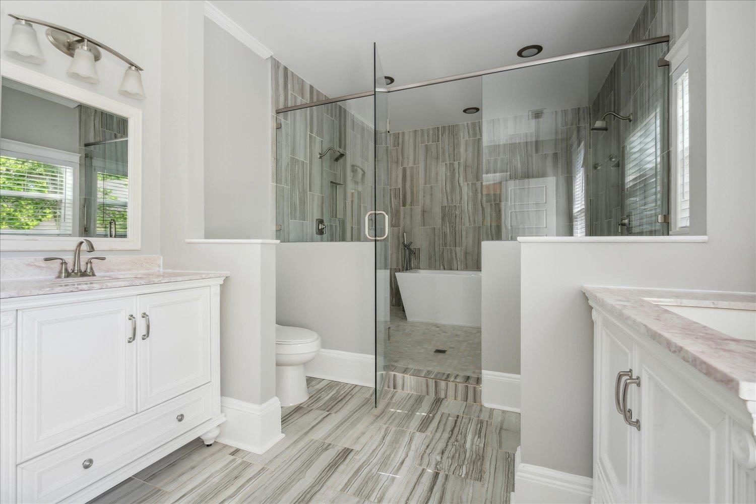 Bathroom with walk in shower, tile floors, toilet, and vanity with extensive cabinet space and a second walk-in closet