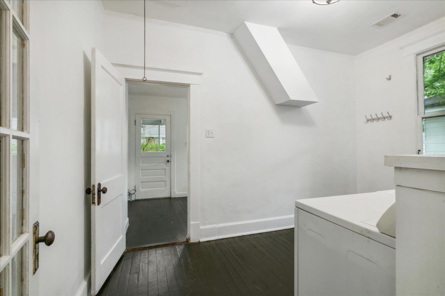 Washroom featuring a healthy amount of sunlight, dark wood-type flooring, a skylight, and washer / clothes dryer