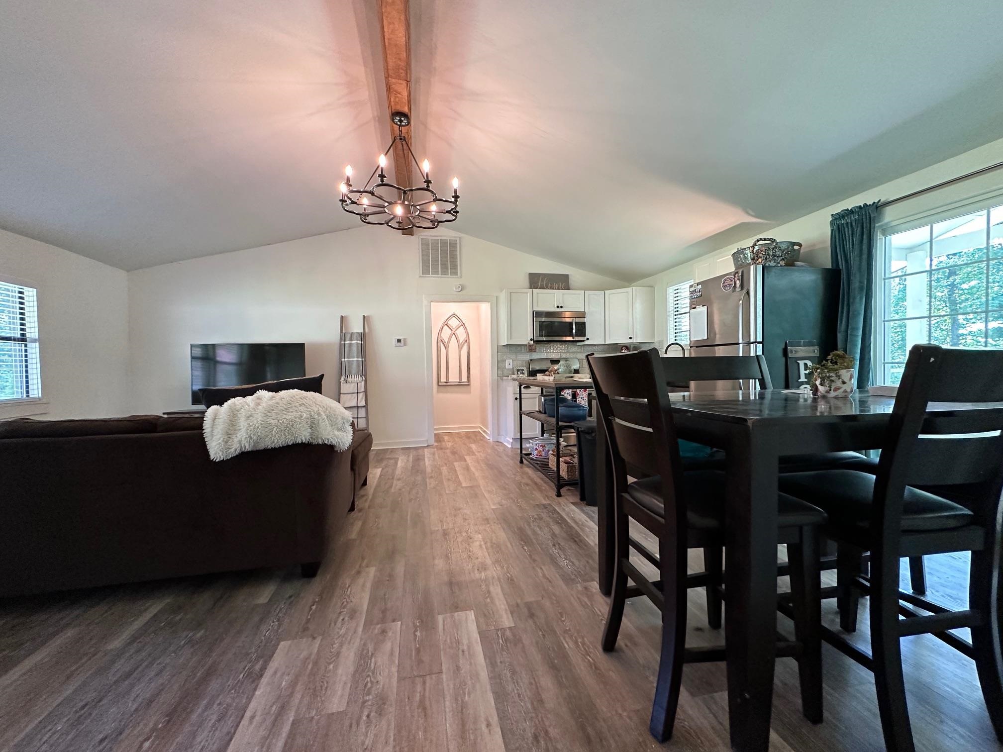 Dining area with a chandelier, vaulted ceiling with beams, and hardwood / wood-style floors