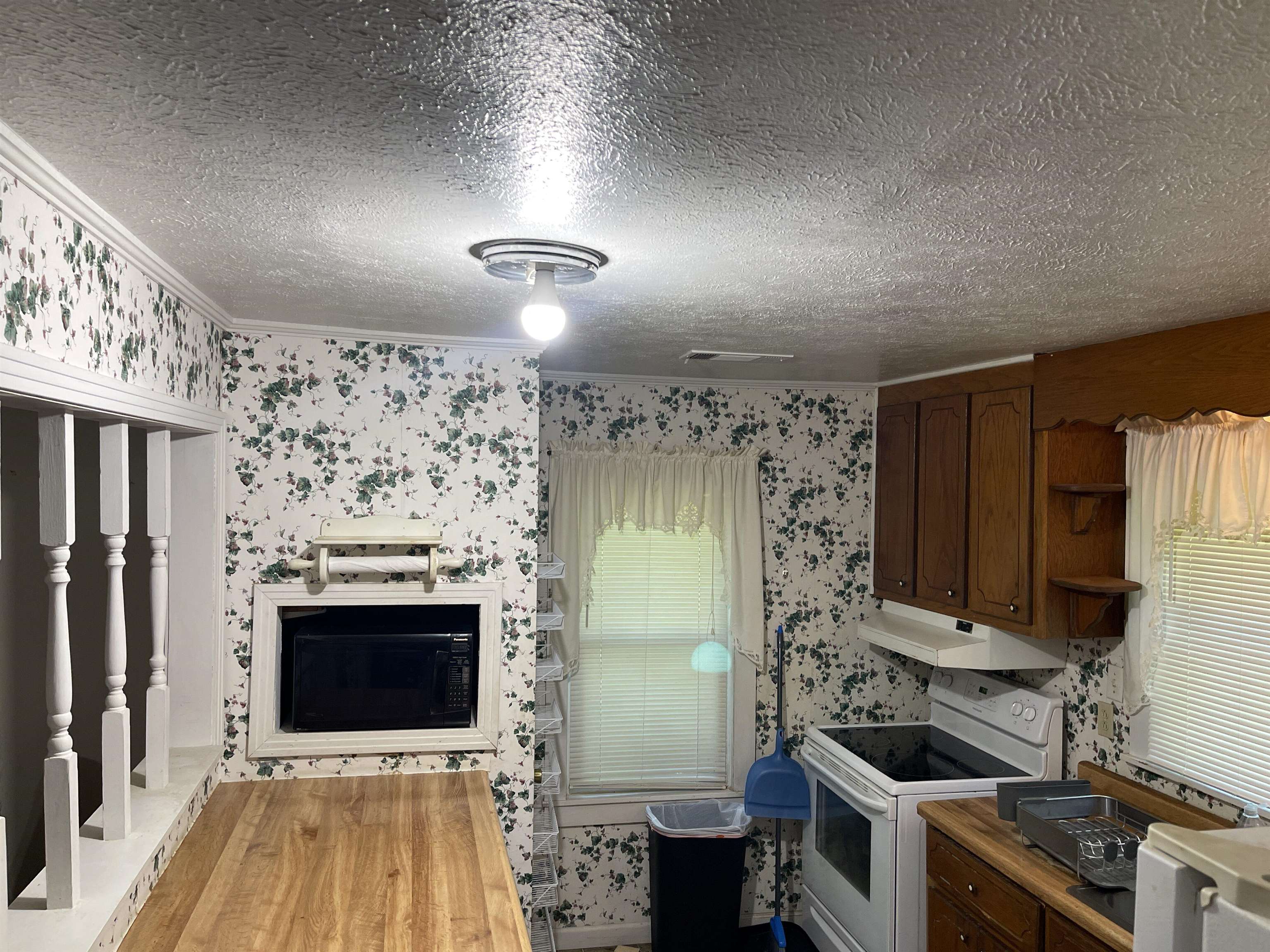 Kitchen with white electric range oven, hardwood / wood-style floors, a textured ceiling, and butcher block countertops