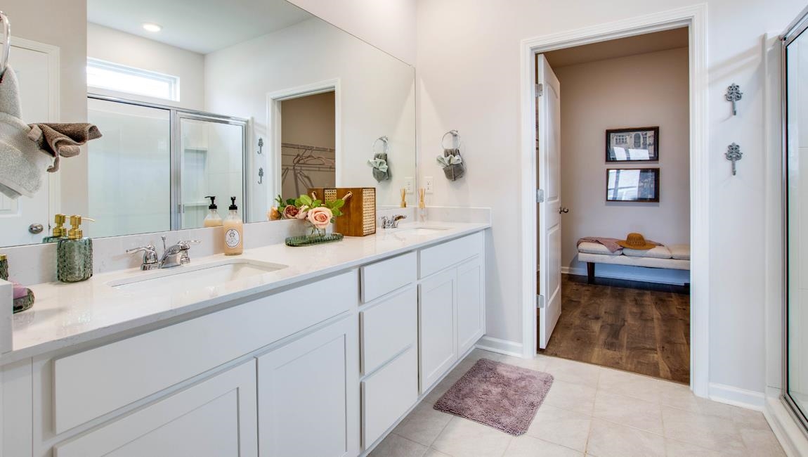 Bathroom with hardwood / wood-style floors, an enclosed shower, dual sinks, and vanity with extensive cabinet space