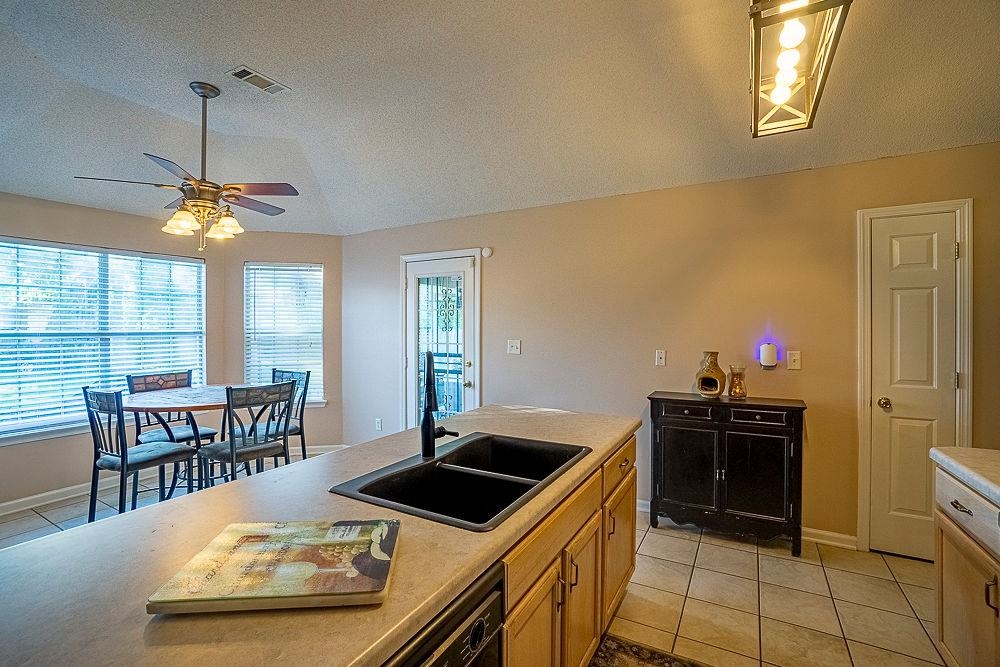 Kitchen with ceiling fan, sink, lofted ceiling, and light tile floors