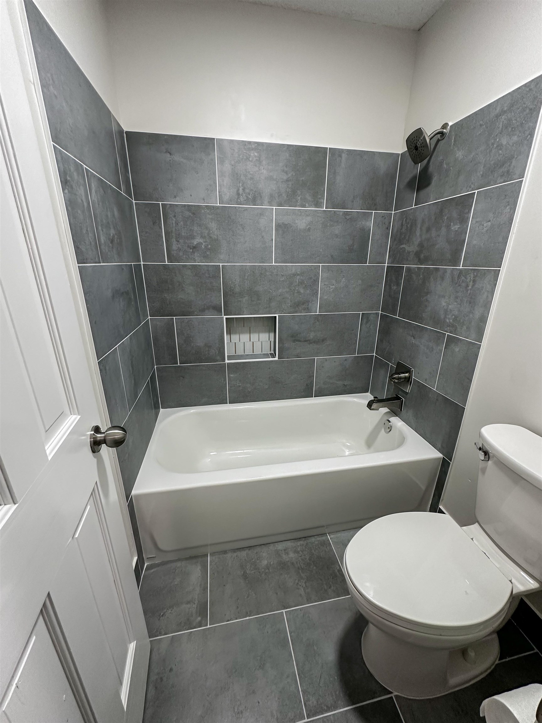 Bathroom with tiled shower / bath, tile flooring, and toilet