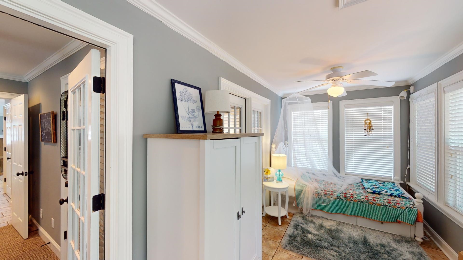 Tiled bedroom featuring ornamental molding and ceiling fan