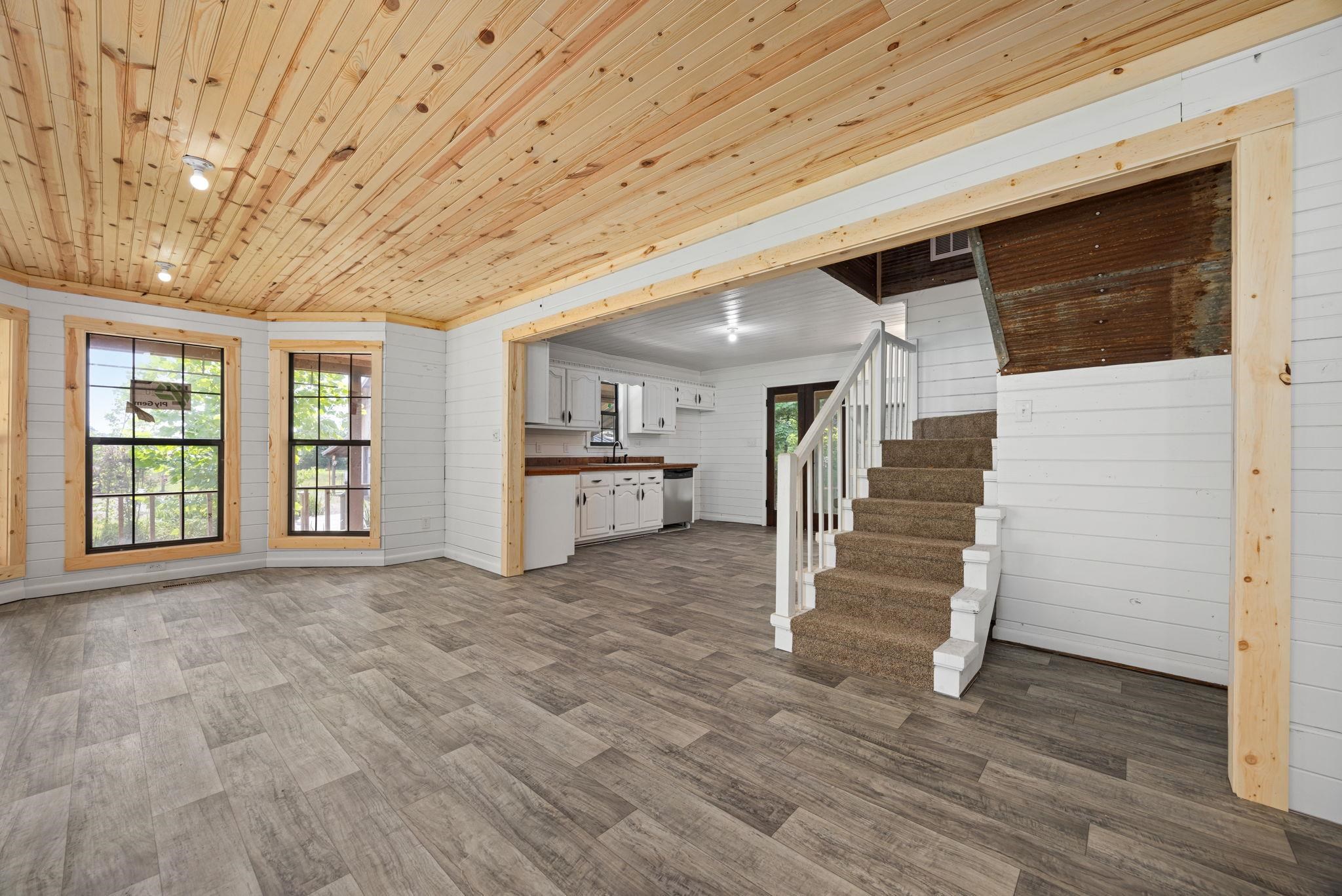 Unfurnished living room with a wealth of natural light, wooden ceiling, and dark hardwood / wood-style floors