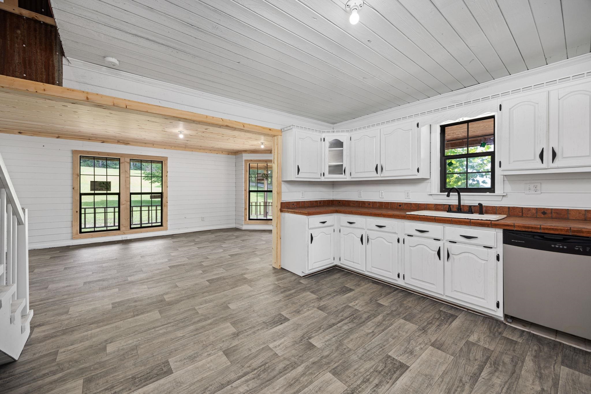 Kitchen with white cabinetry, hardwood / wood-style floors, wooden counters, sink, and dishwasher