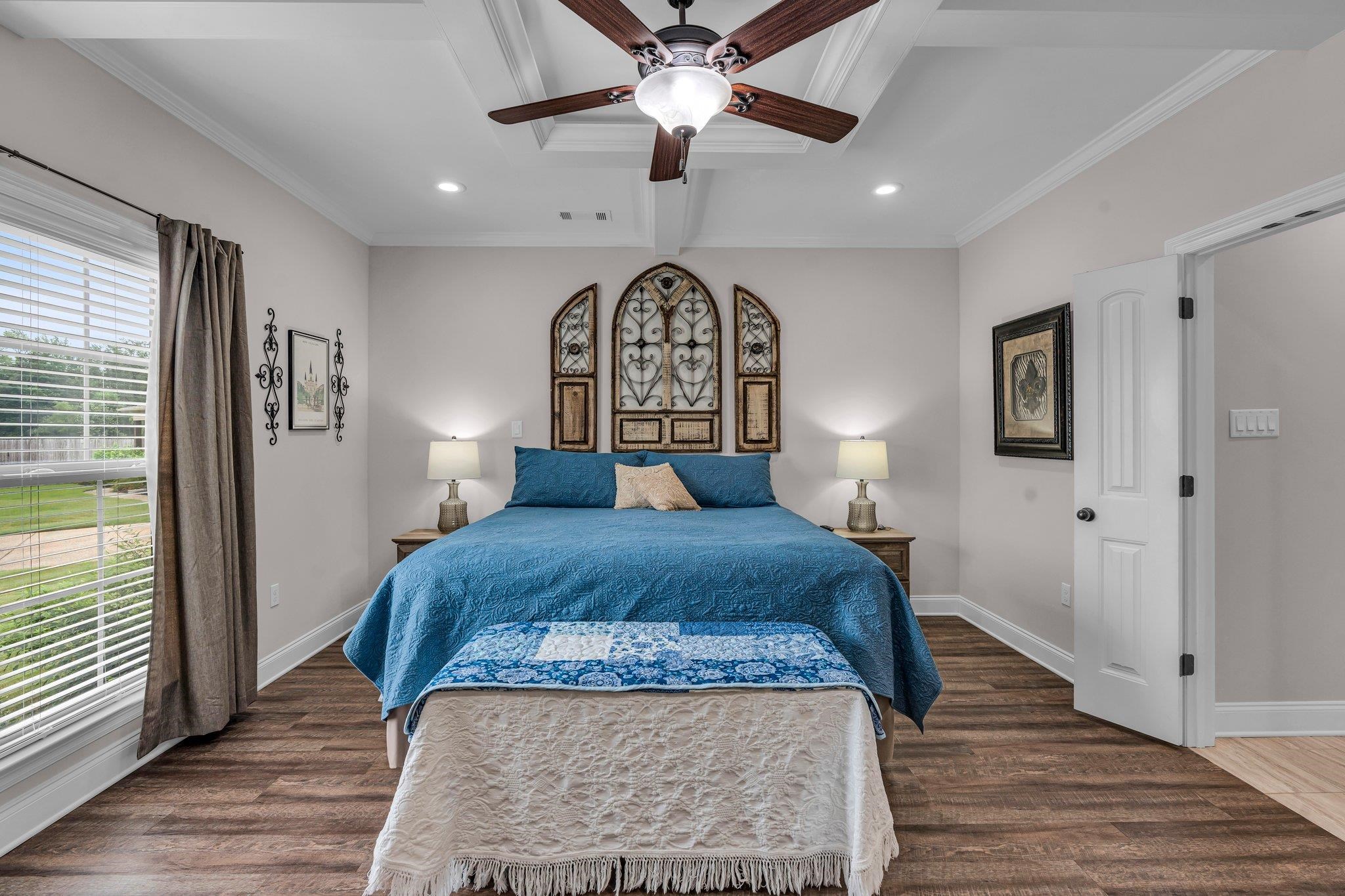 Bedroom with ceiling fan, ornamental molding, multiple windows, and dark hardwood / wood-style flooring