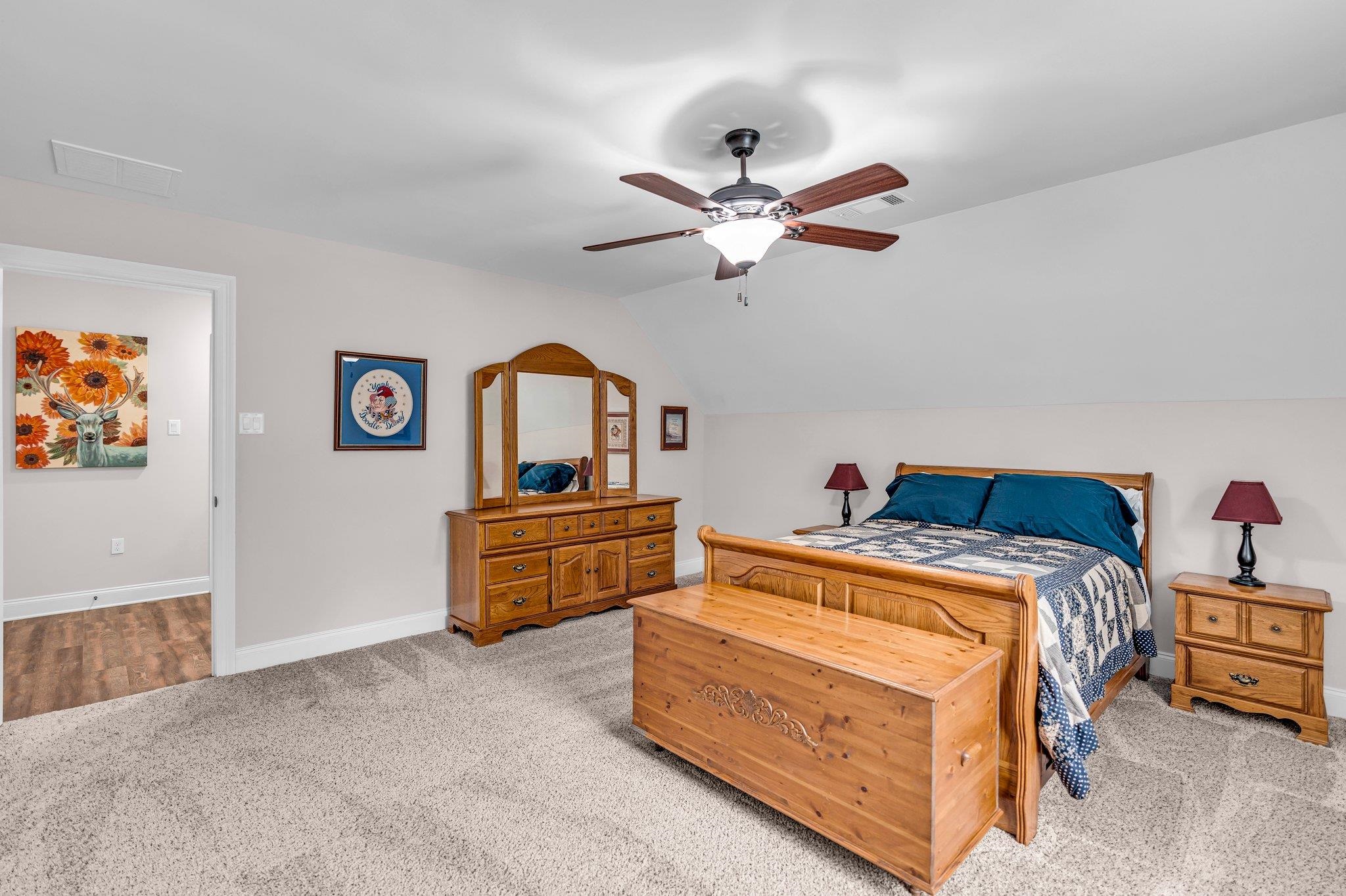 Carpeted bedroom featuring vaulted ceiling and ceiling fan