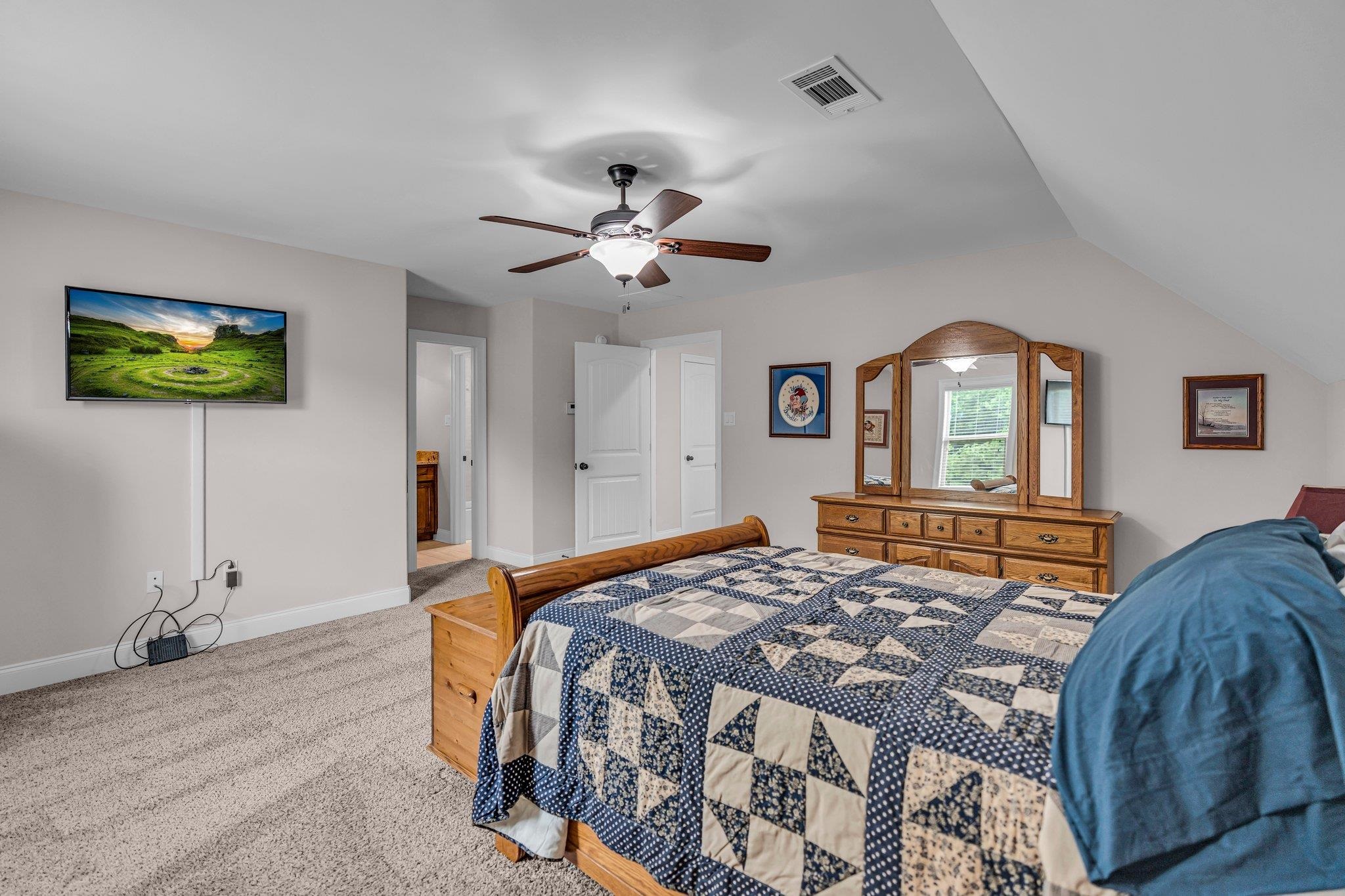 Bedroom with ceiling fan, carpet flooring, and lofted ceiling