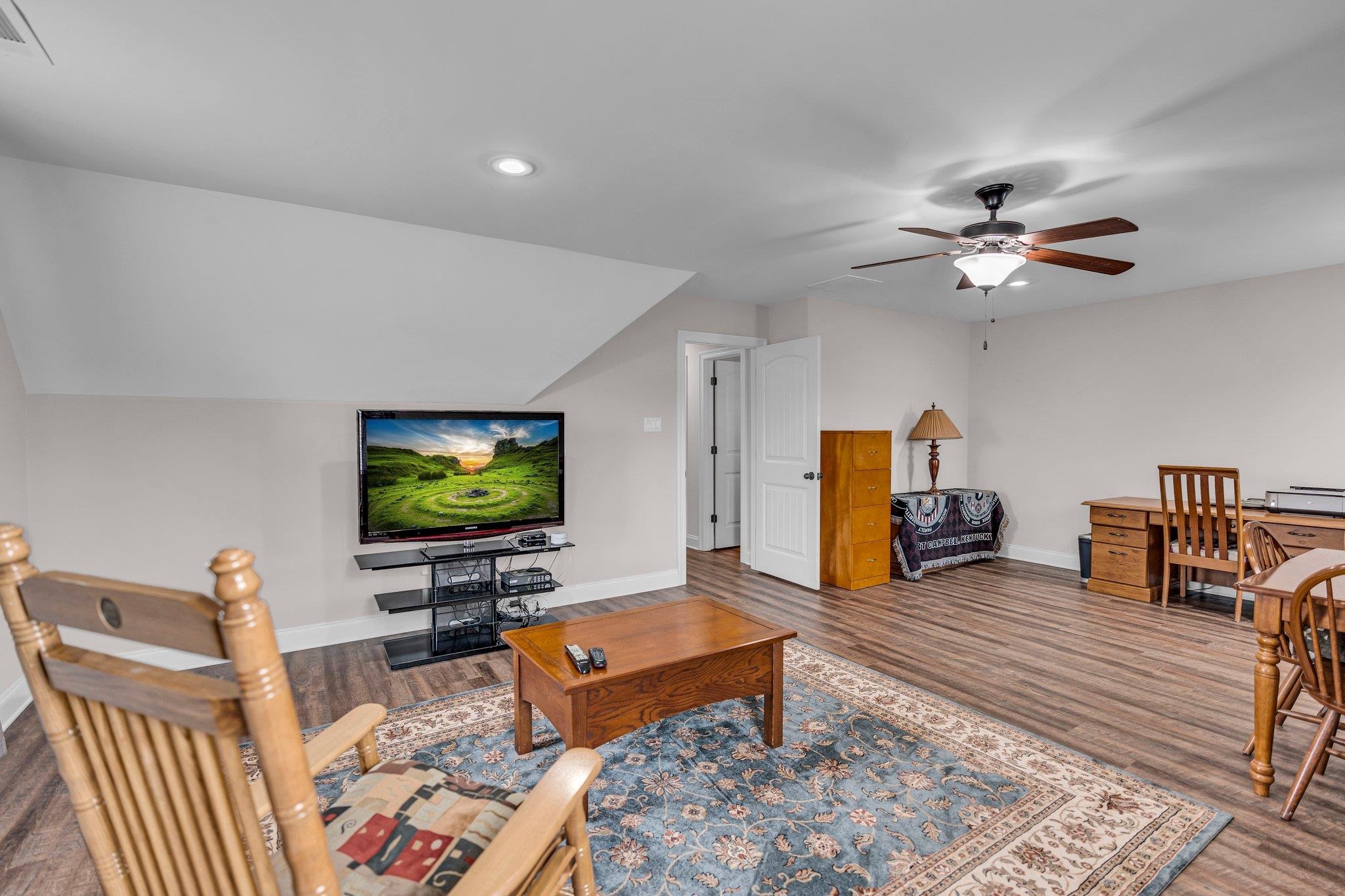 Living room with ceiling fan, lofted ceiling, and wood-type flooring