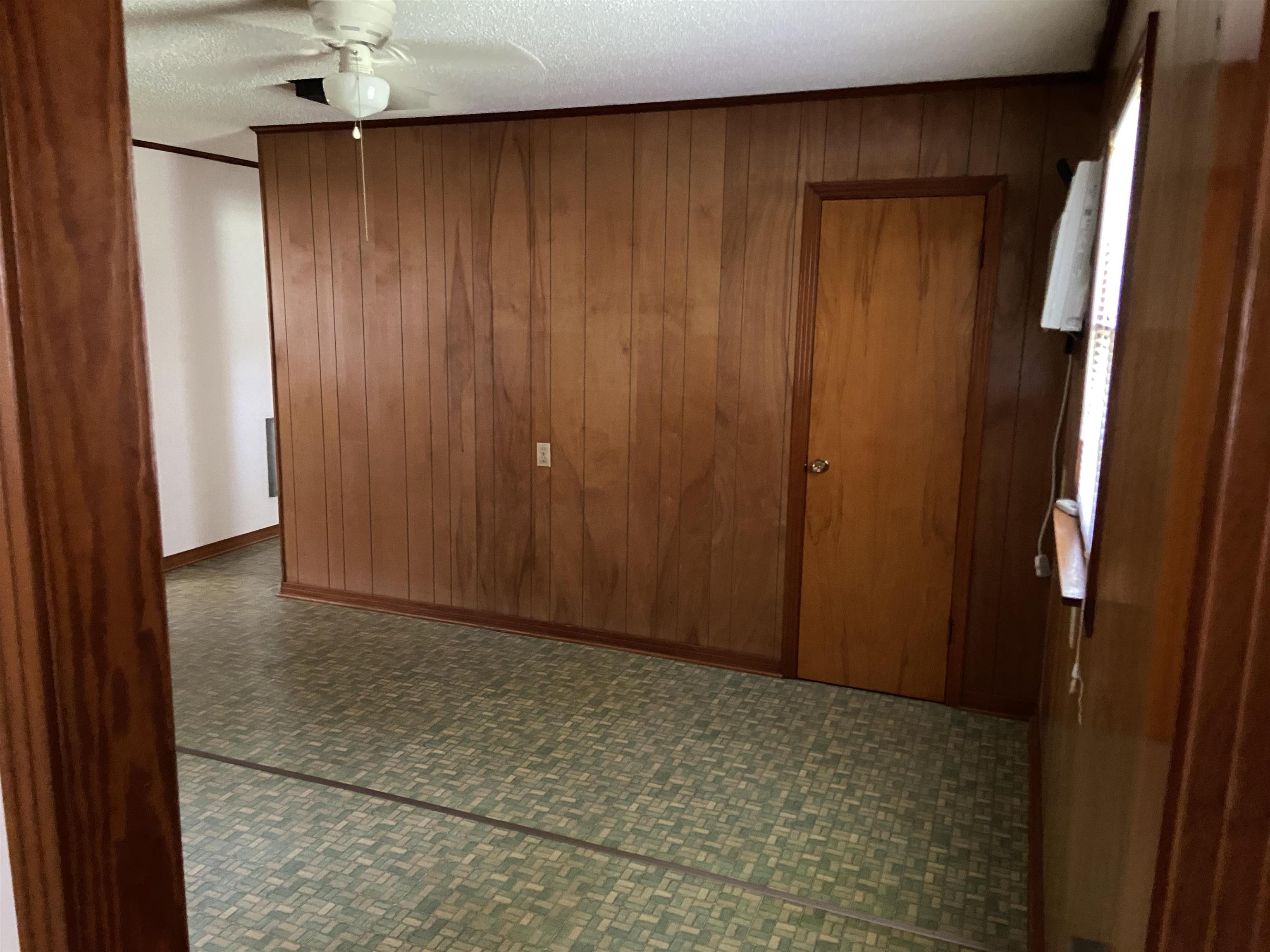 Spare room featuring tile floors, wood walls, ceiling fan, and a textured ceiling