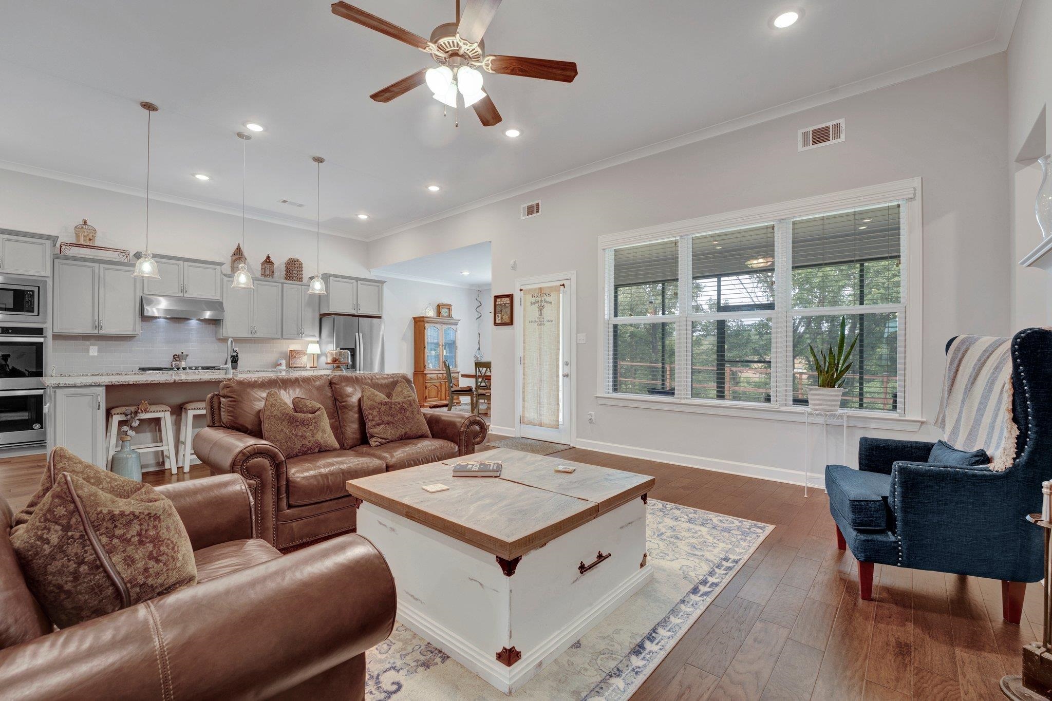 Living room featuring ornamental molding, ceiling fan, and dark wood-type flooring