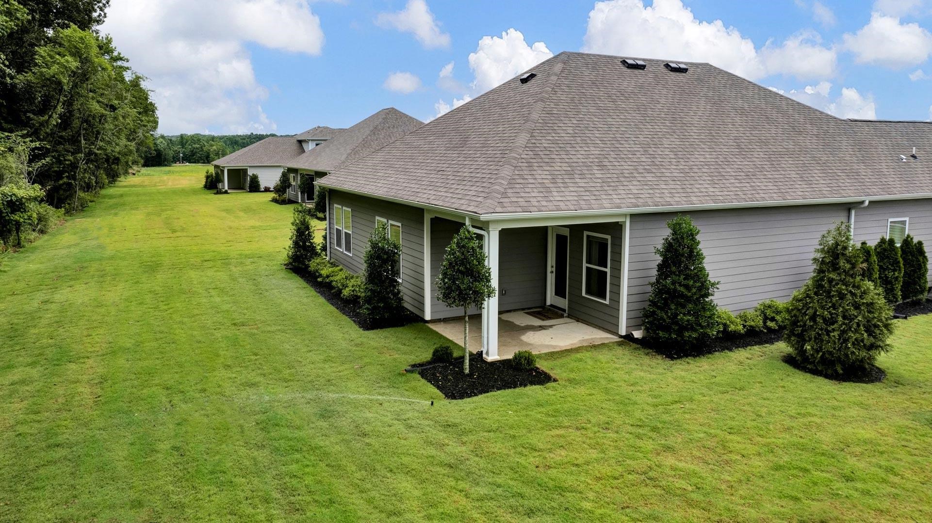 Back of house with a patio area and a lawn