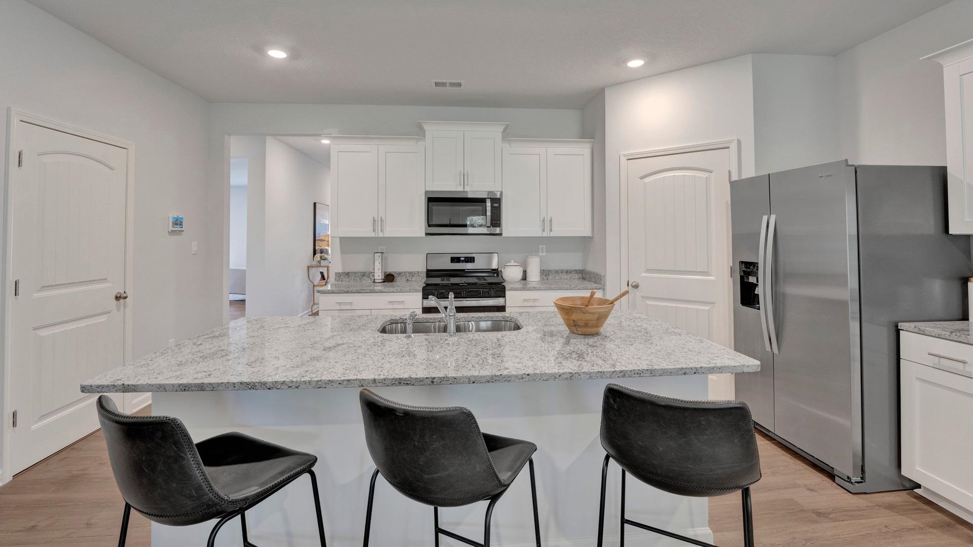 Kitchen with appliances with stainless steel finishes, white cabinetry, an island with sink, and light hardwood / wood-style flooring
