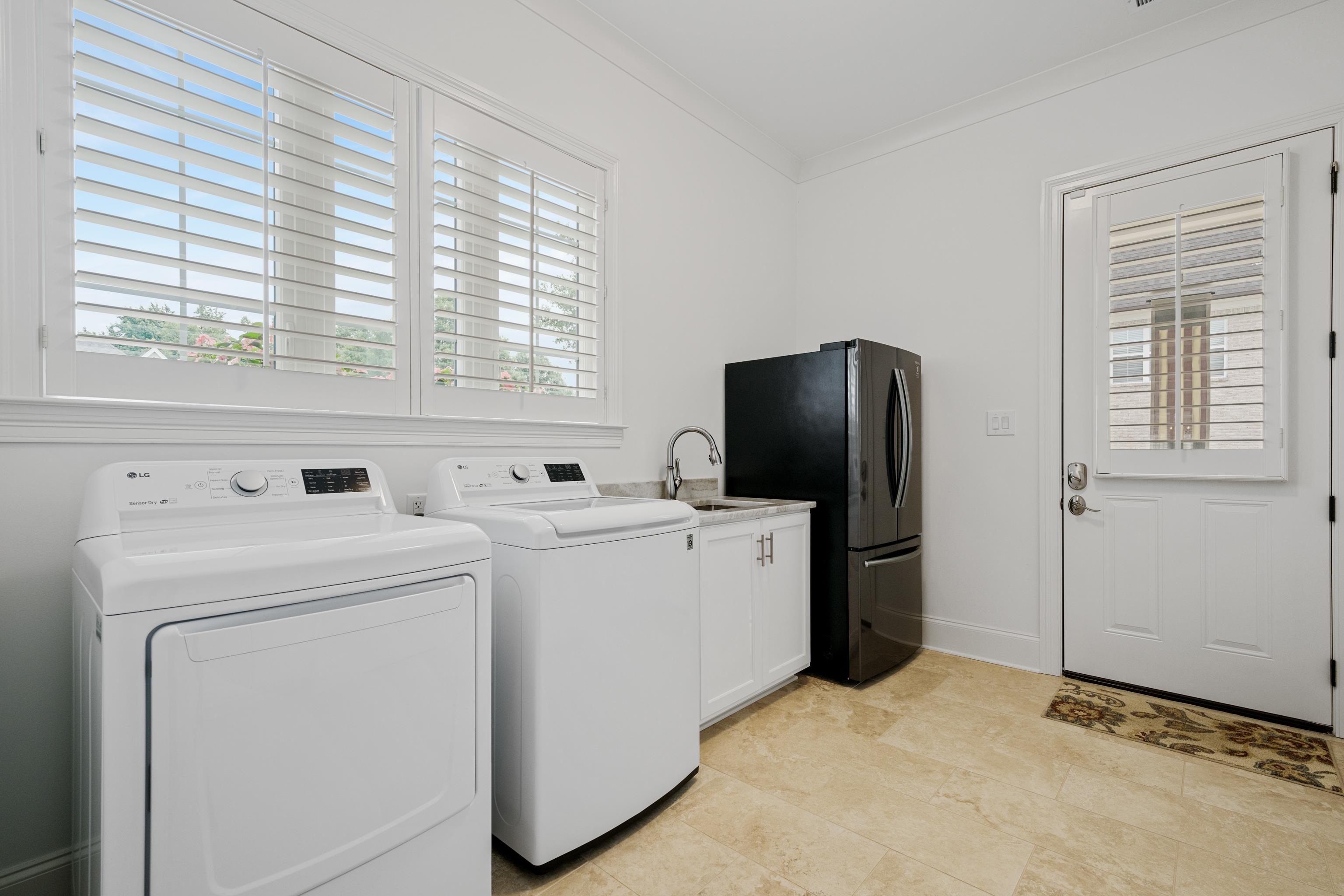 Laundry area featuring cabinets, ornamental molding, washing machine and dryer, and light tile floors