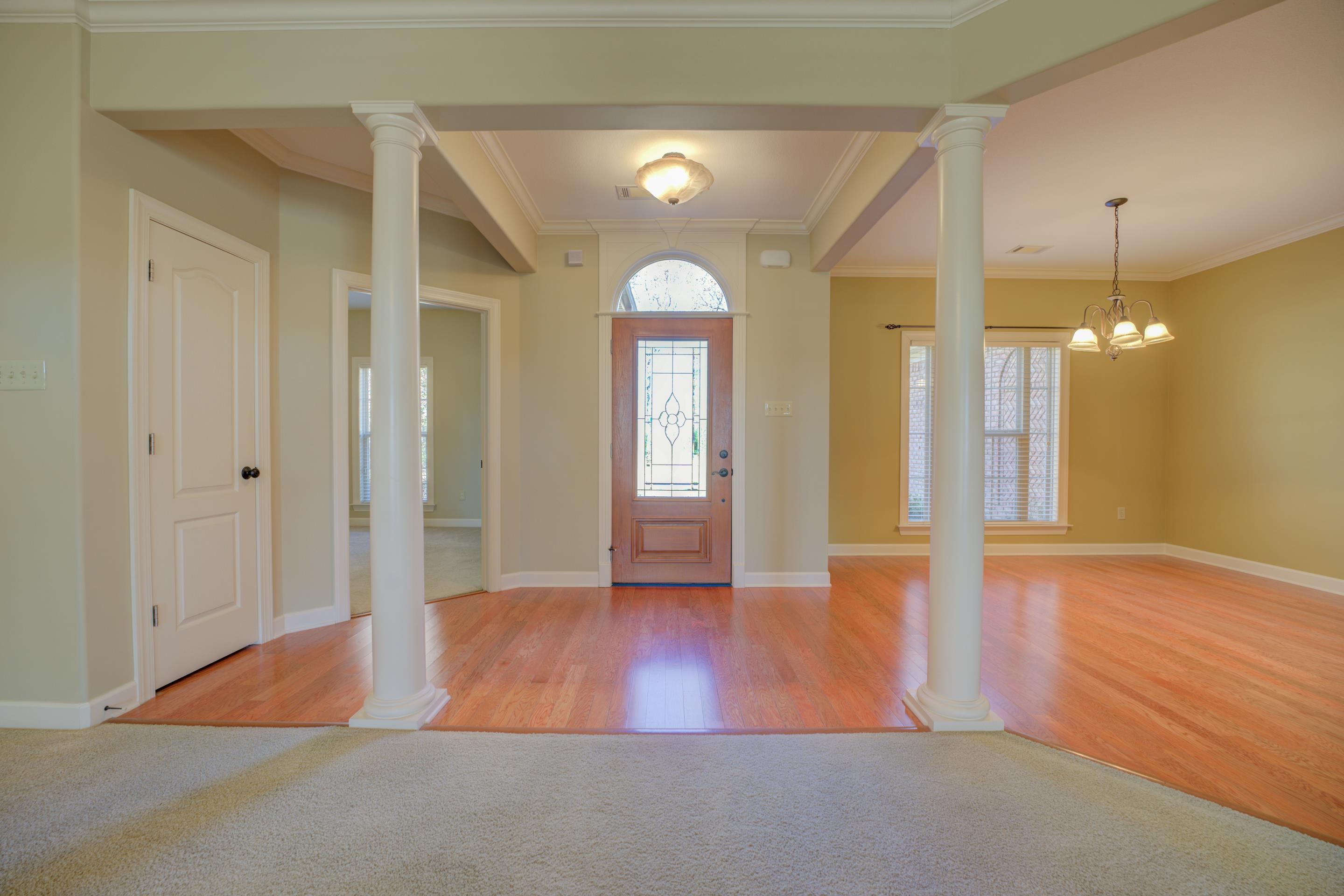 Entrance foyer with wood flooring, ornate columns, ornamental molding, and an inviting chandelier