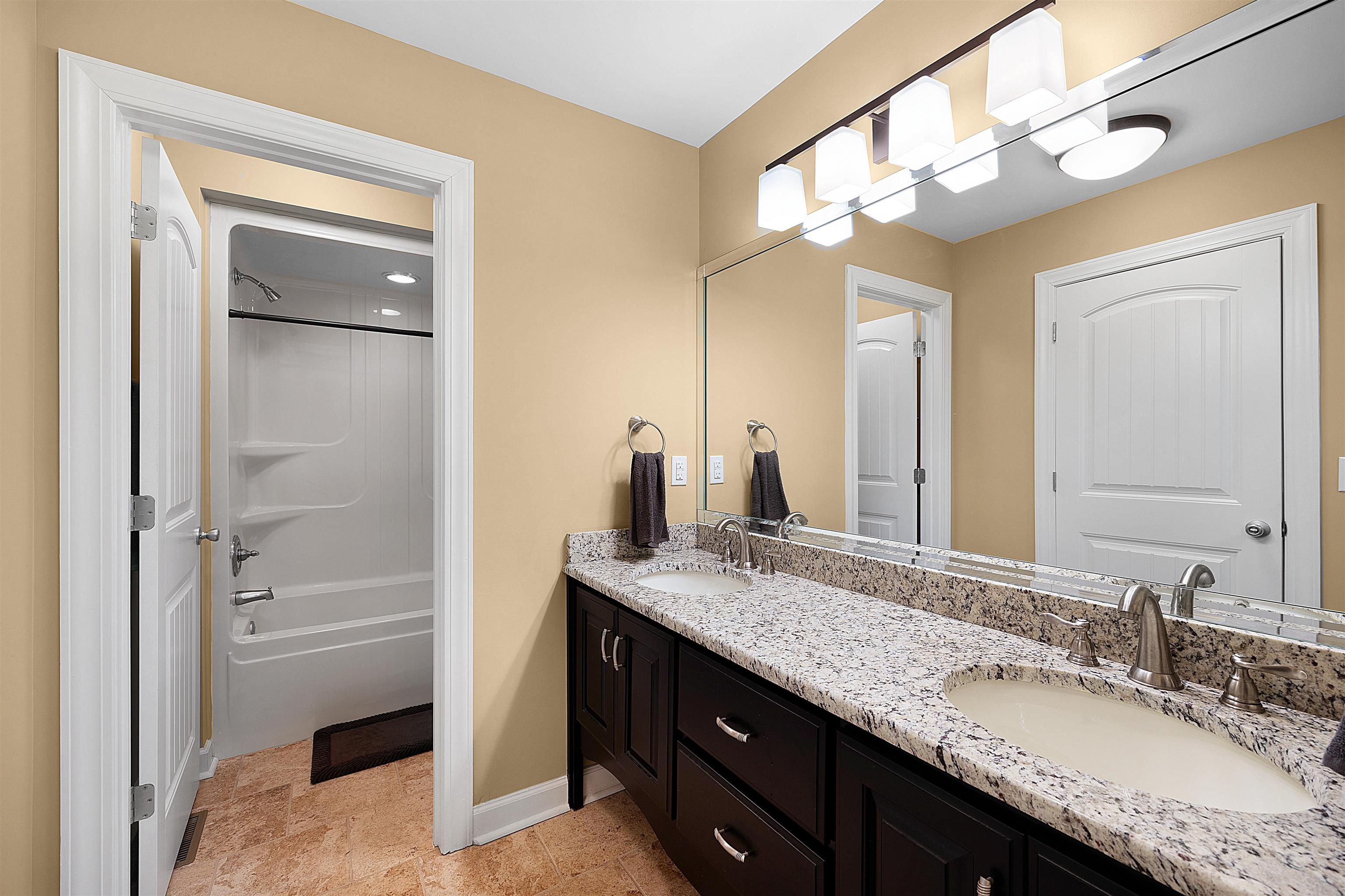 Bathroom with tile flooring, shower / tub combination, and double sink vanity