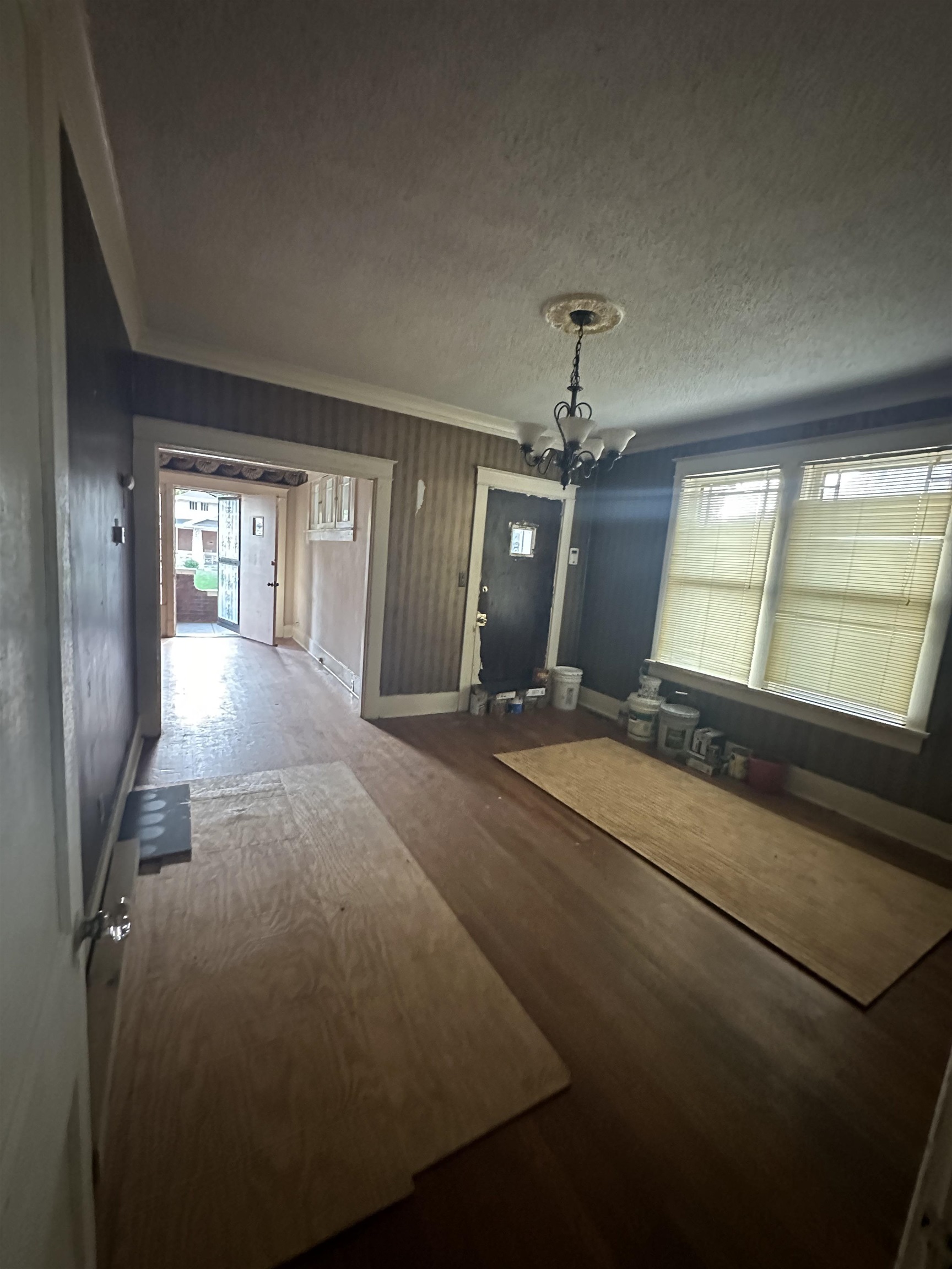 Unfurnished bedroom featuring crown molding, a textured ceiling, a chandelier, and wood-type flooring