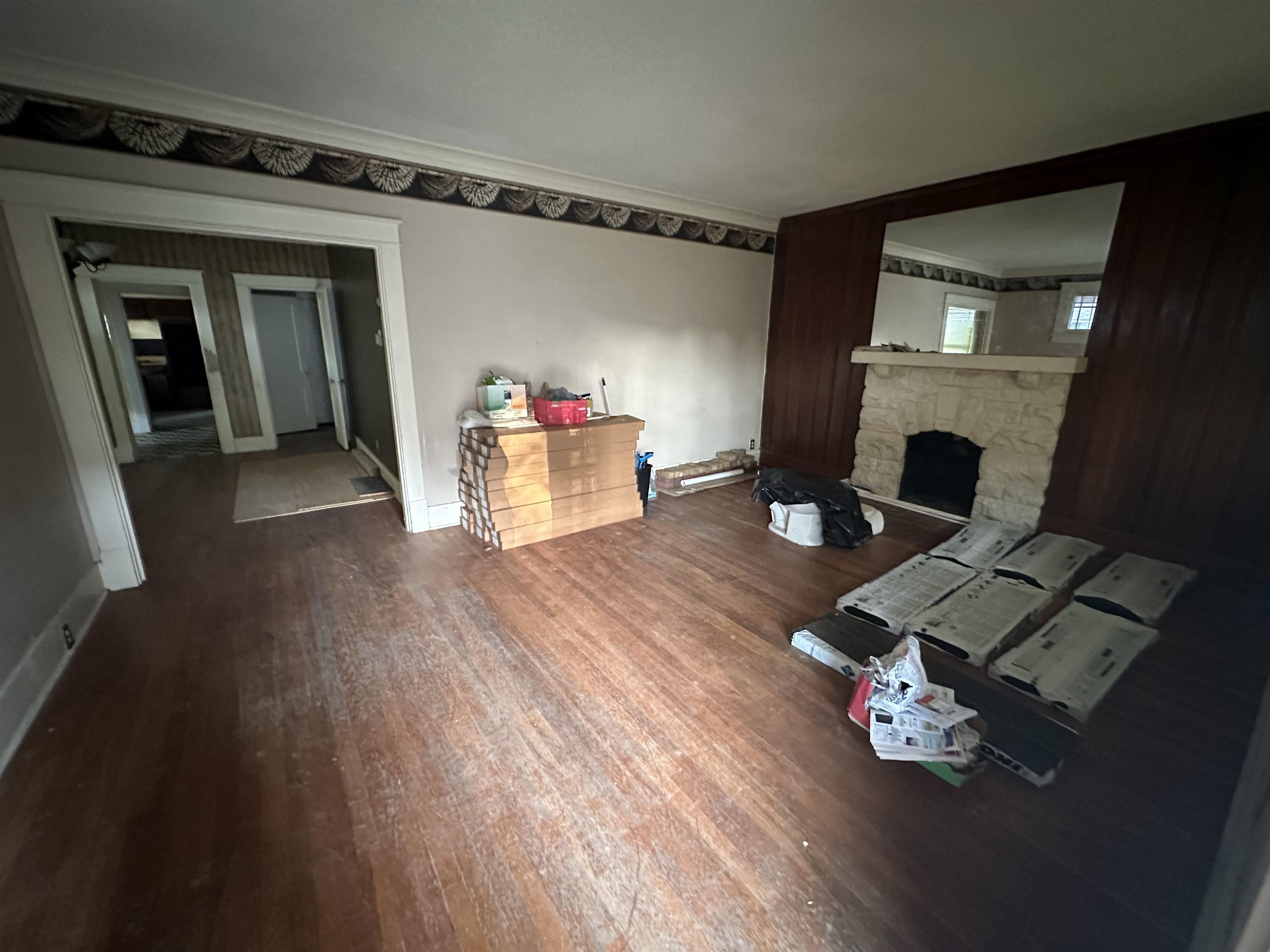 Living room with a stone fireplace, dark hardwood / wood-style flooring, and crown molding