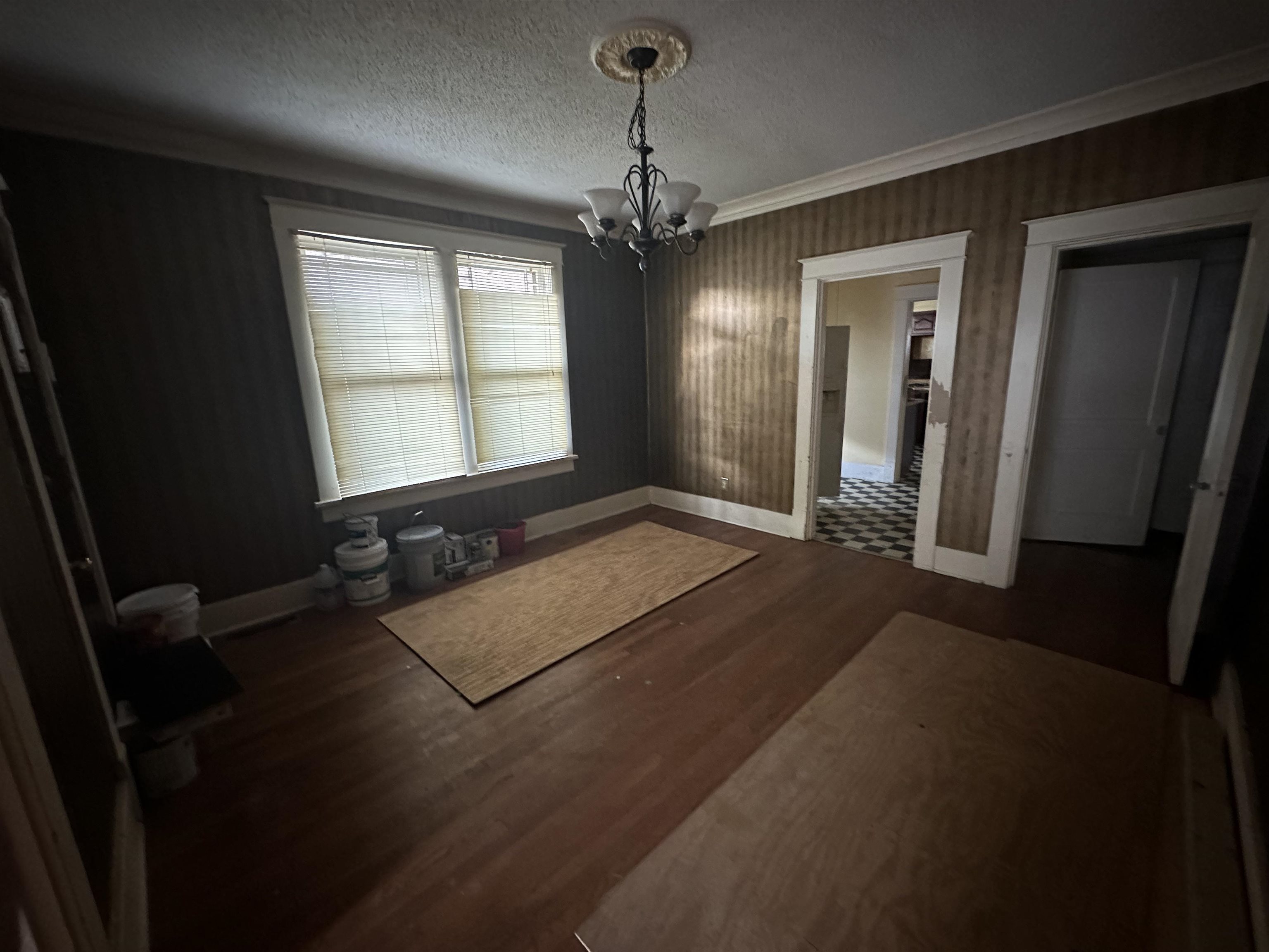 Unfurnished dining area featuring dark tile floors, a chandelier, a textured ceiling, and crown molding