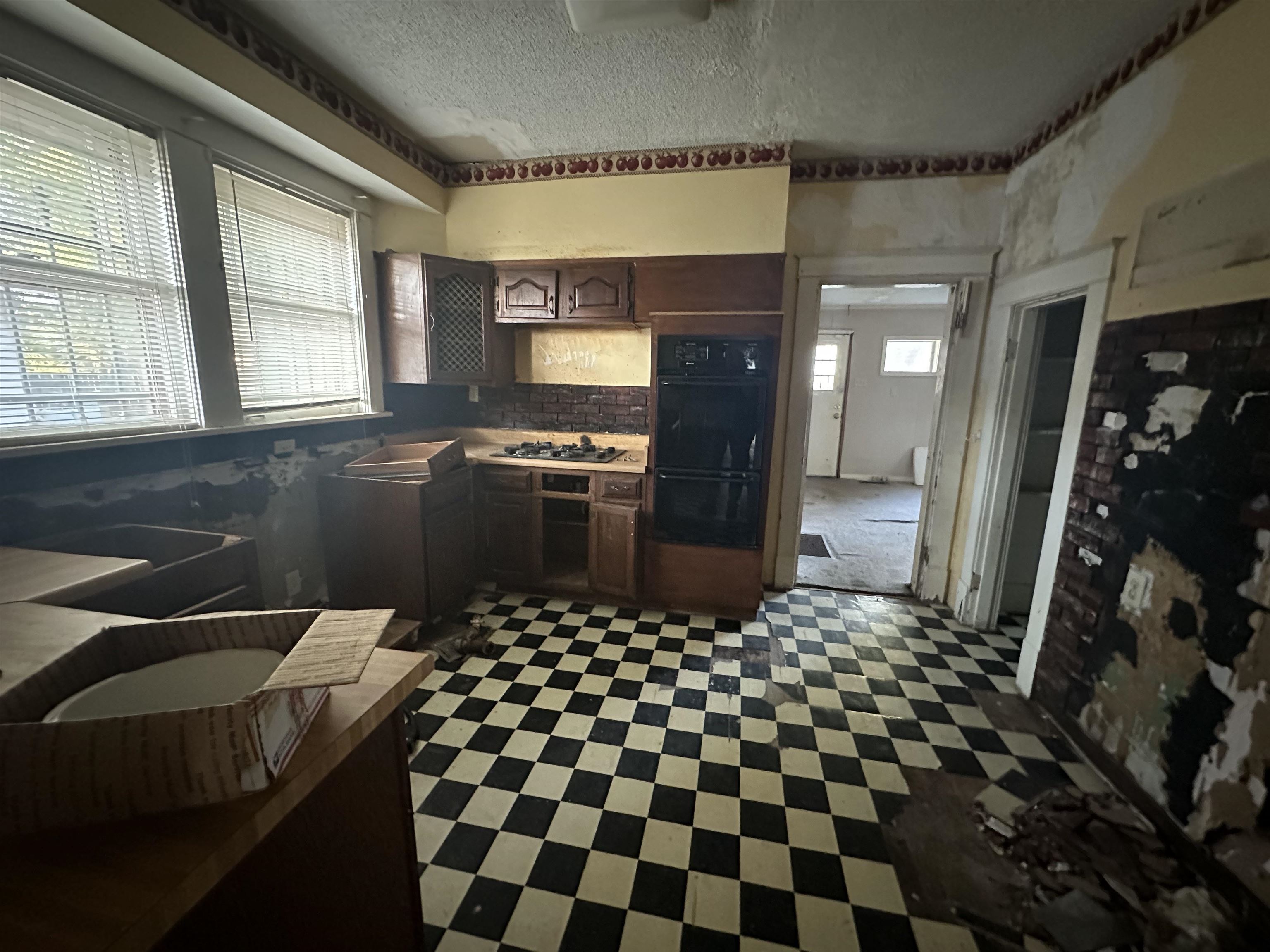 Kitchen with dark tile flooring, dark brown cabinets, stainless steel gas stovetop, and backsplash