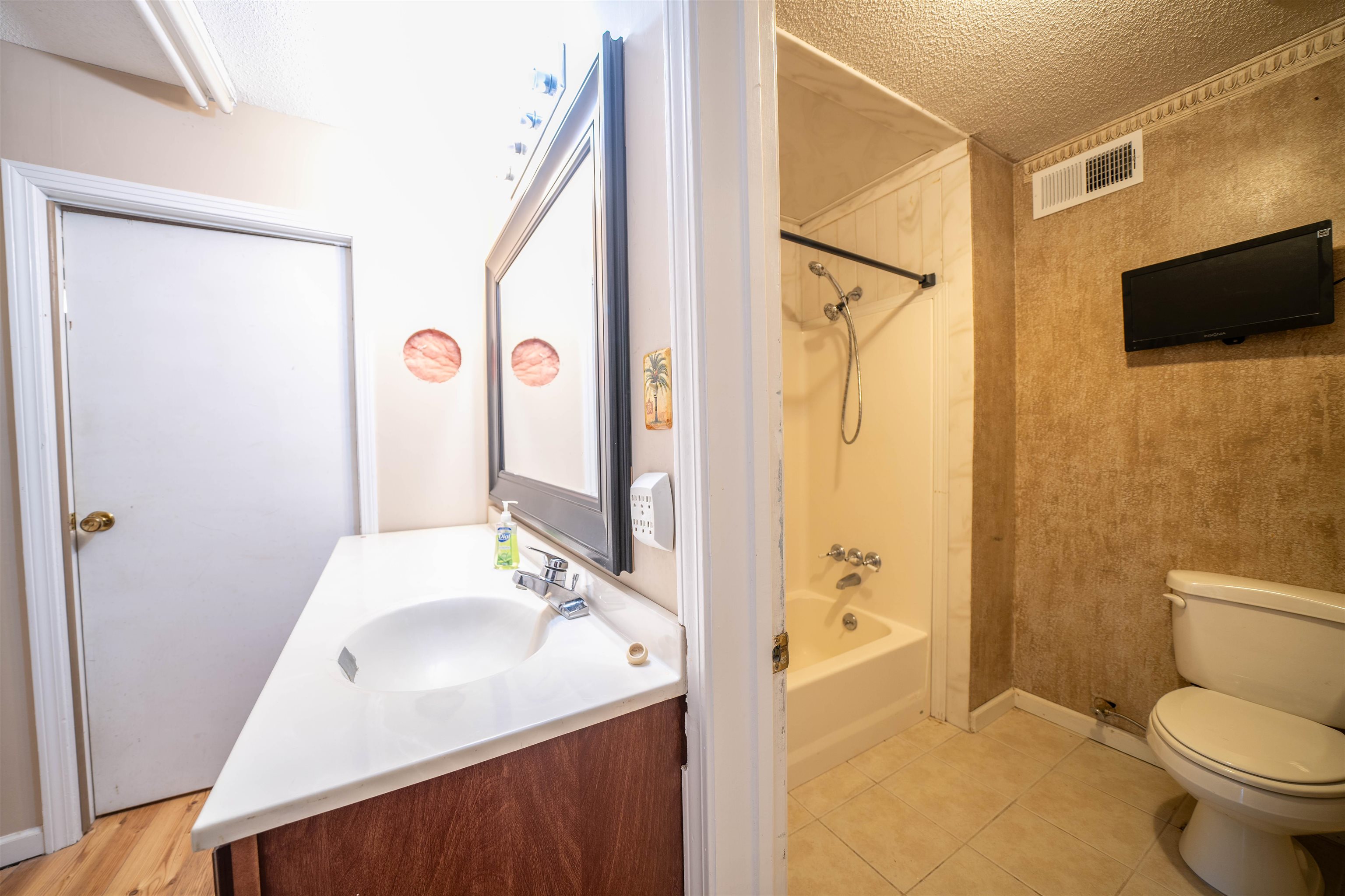 Full bathroom with washtub / shower combination, toilet, tile floors, vanity, and a textured ceiling