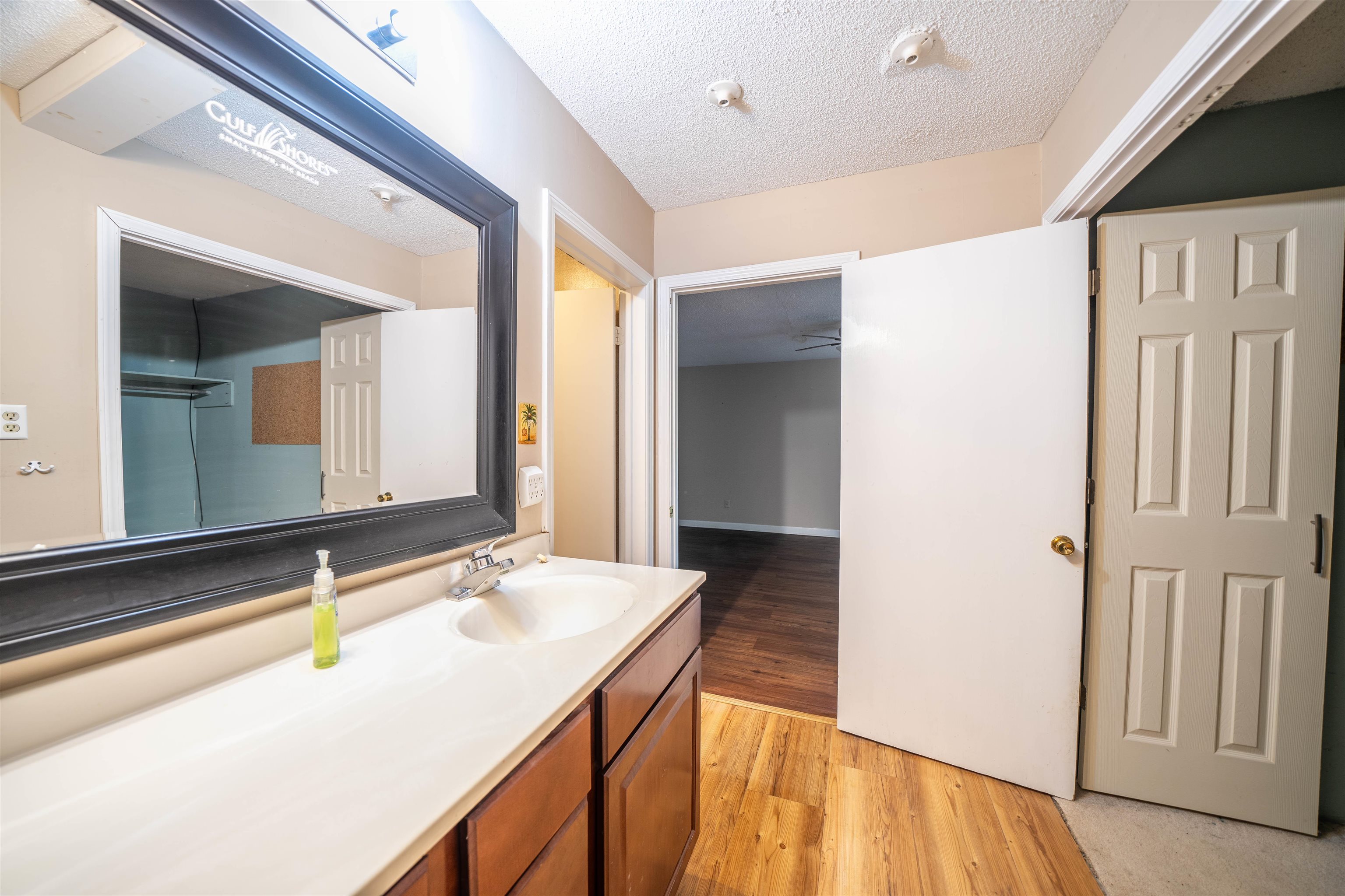Bathroom with hardwood / wood-style flooring, a textured ceiling, and vanity with extensive cabinet space