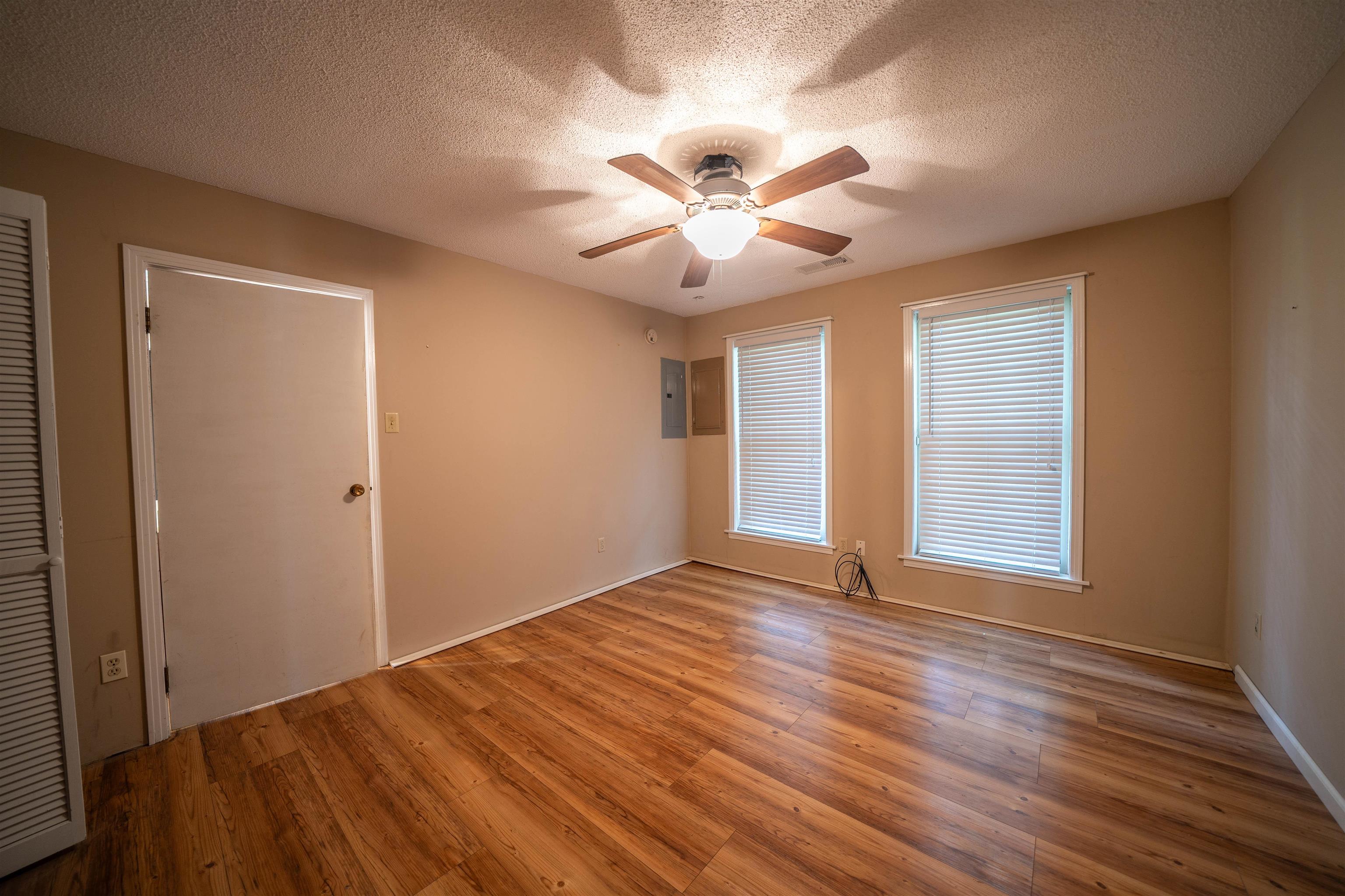 Empty room with a textured ceiling, ceiling fan, and hardwood / wood-style floors