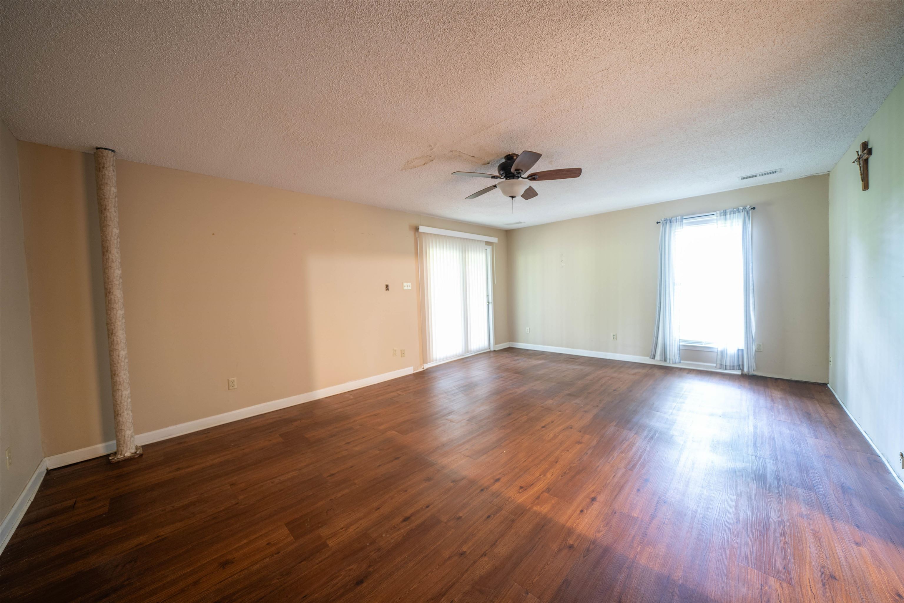 Empty room featuring dark hardwood / wood-style flooring, ceiling fan, and a textured ceiling