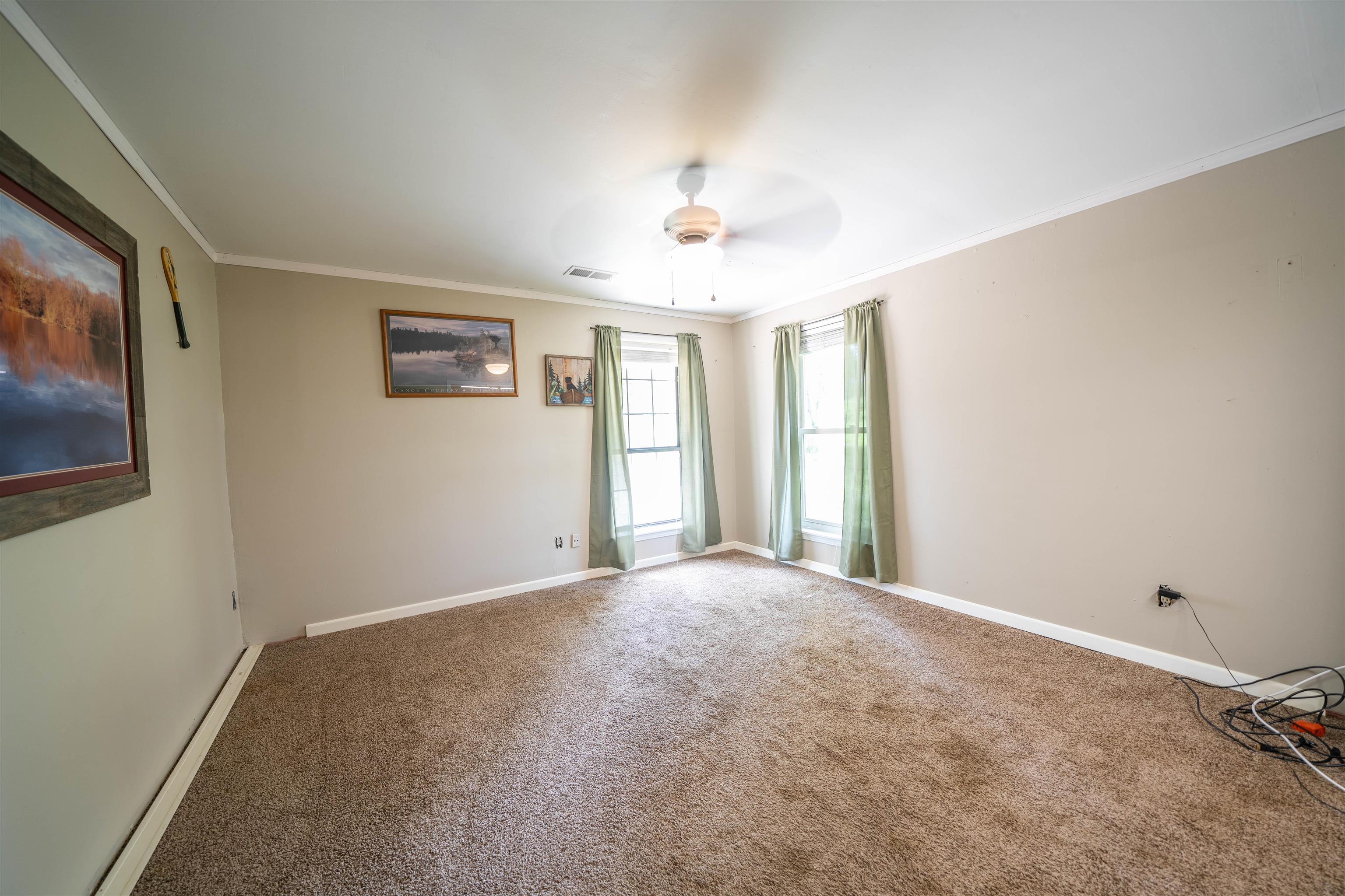 Carpeted spare room featuring crown molding and ceiling fan