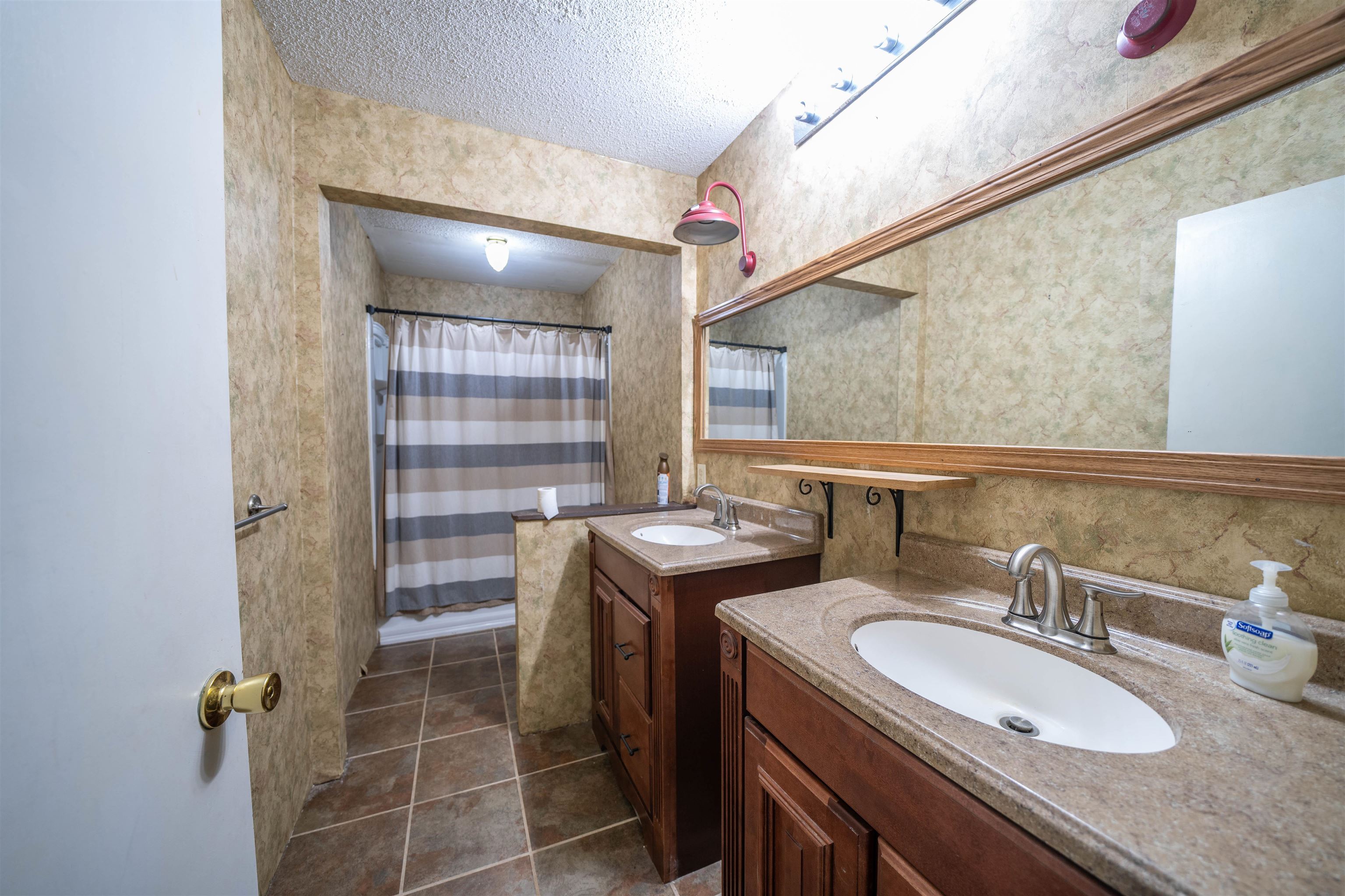 Bathroom with double sink, a textured ceiling, tile flooring, and vanity with extensive cabinet space