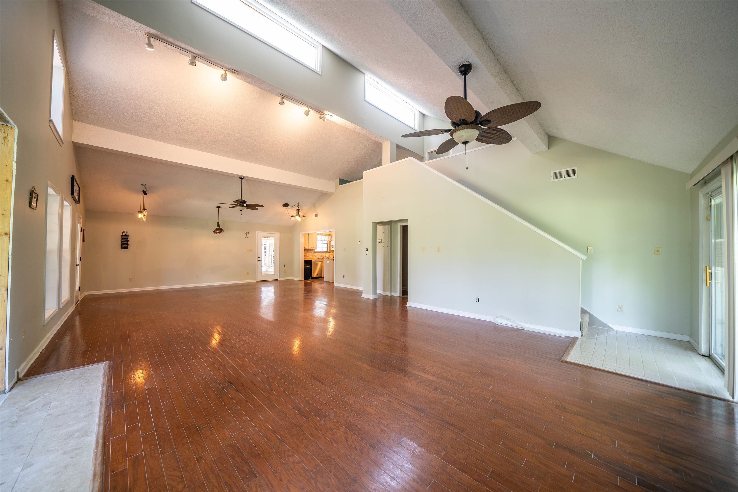Unfurnished living room with ceiling fan, plenty of natural light, beam ceiling, and hardwood / wood-style floors