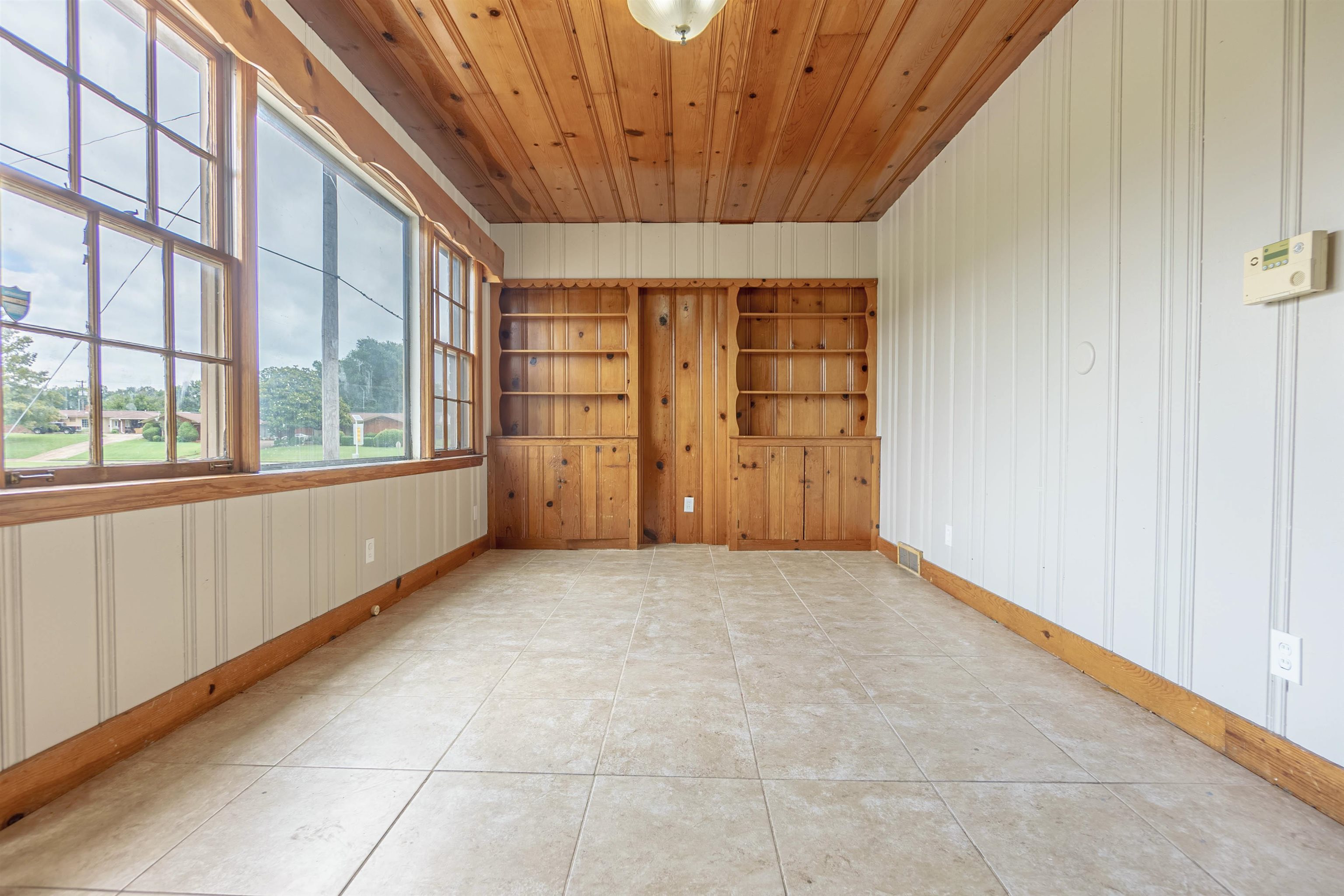 Empty room with wooden ceiling and light tile flooring