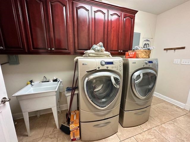 Laundry room featuring cabinets, light tile flooring, and washer and clothes dryer