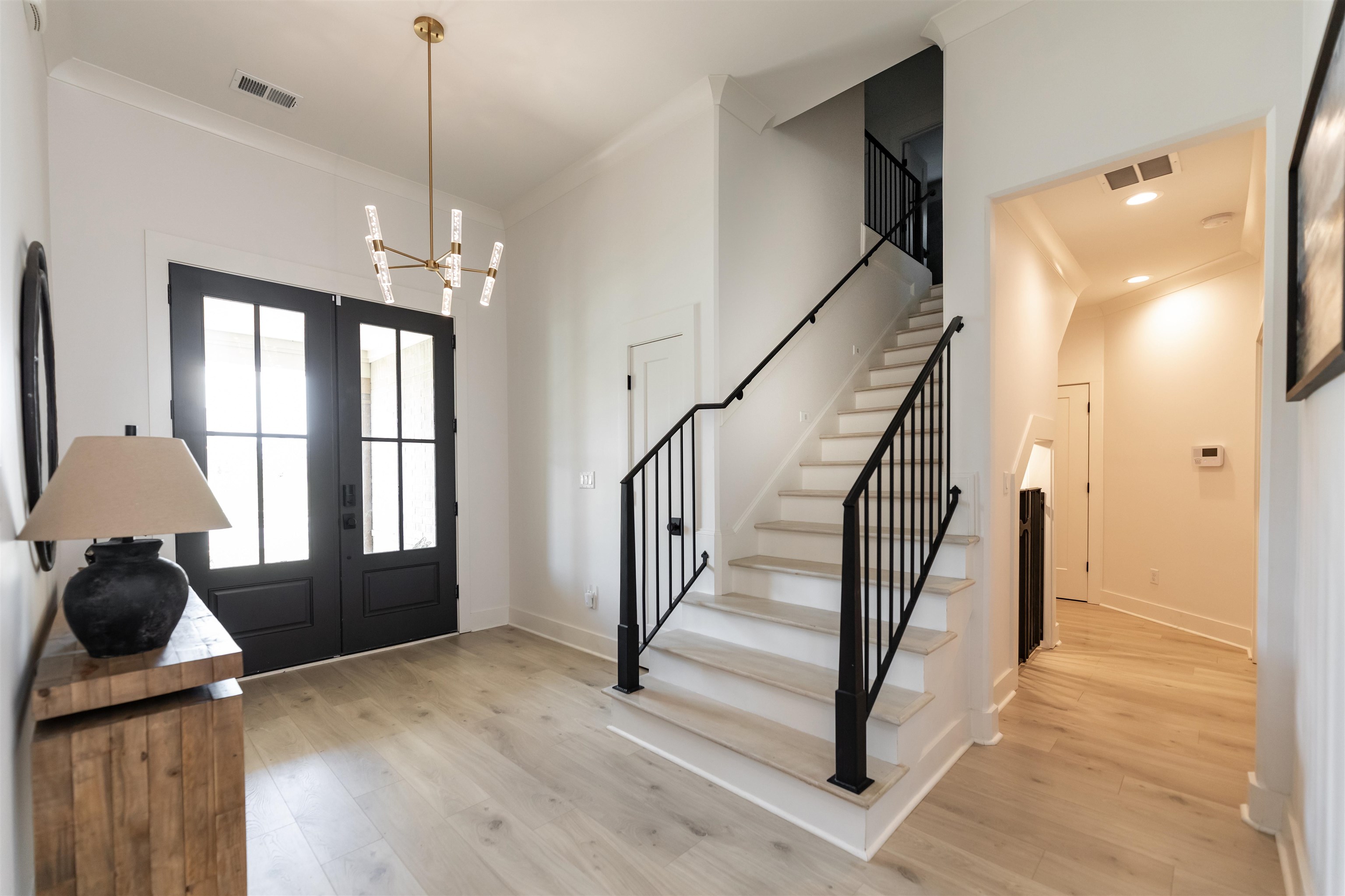 Entrance foyer with a notable chandelier, light hardwood / wood-style floors, and french doors
