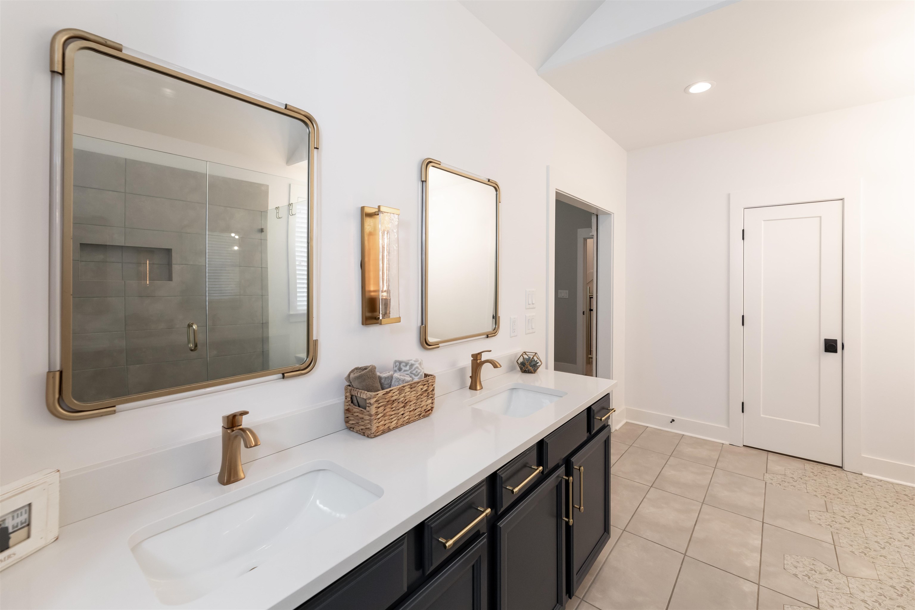 Bathroom with double vanity, walk in shower, tile flooring, and lofted ceiling