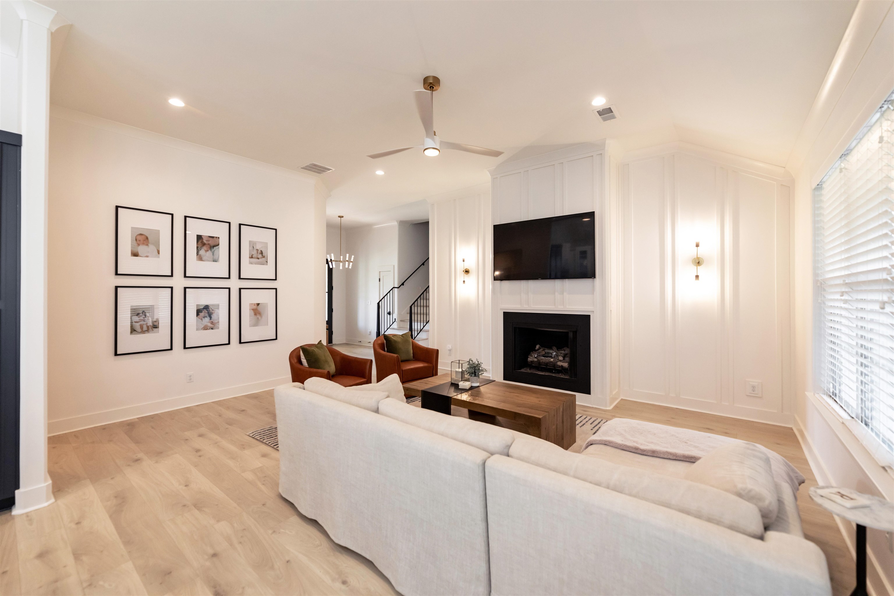 Living room featuring ceiling fan with notable chandelier and light hardwood / wood-style flooring