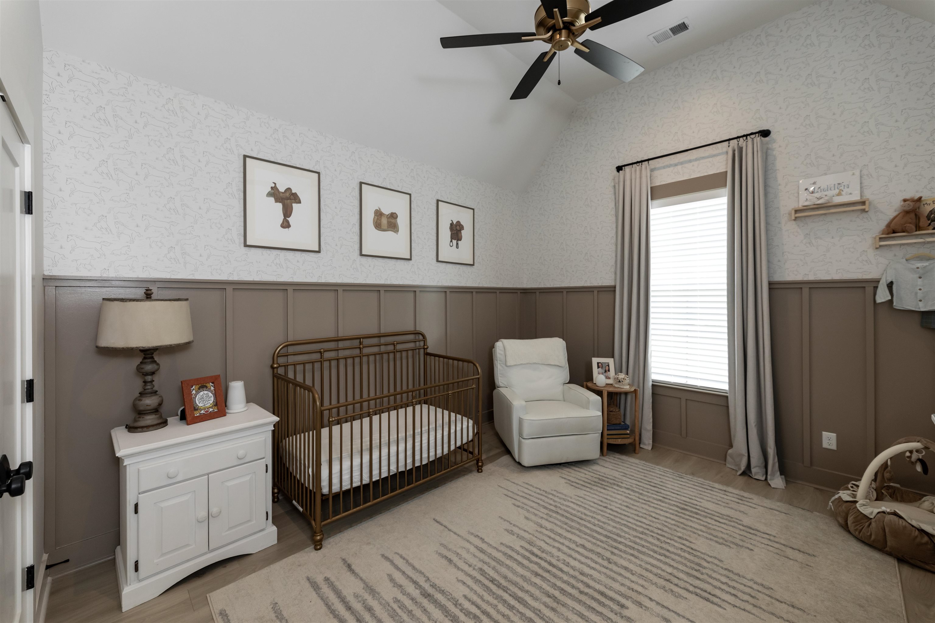 Bedroom featuring vaulted ceiling, a crib, and ceiling fan