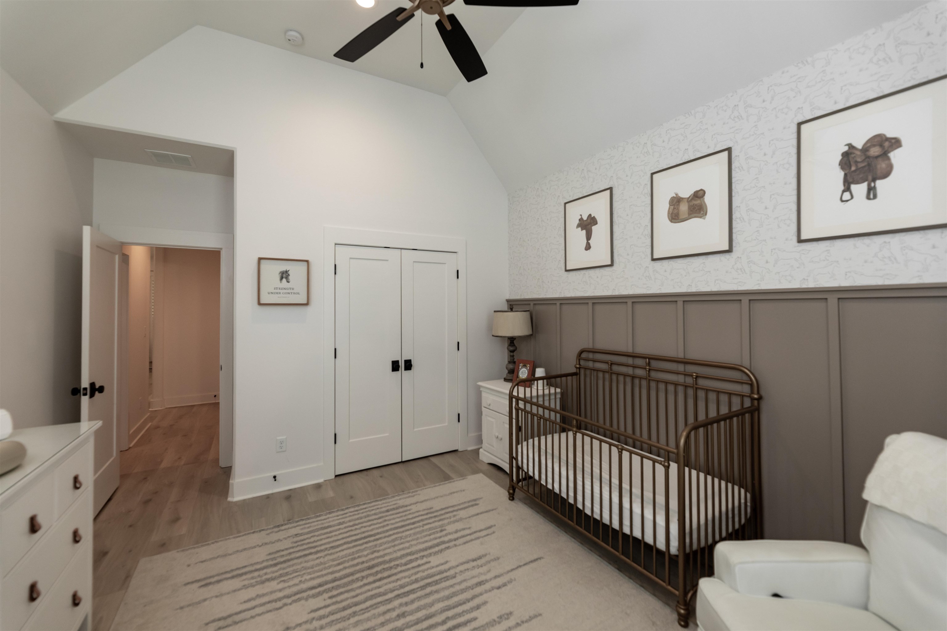 Bedroom featuring a nursery area, lofted ceiling, hardwood / wood-style flooring, a closet, and ceiling fan