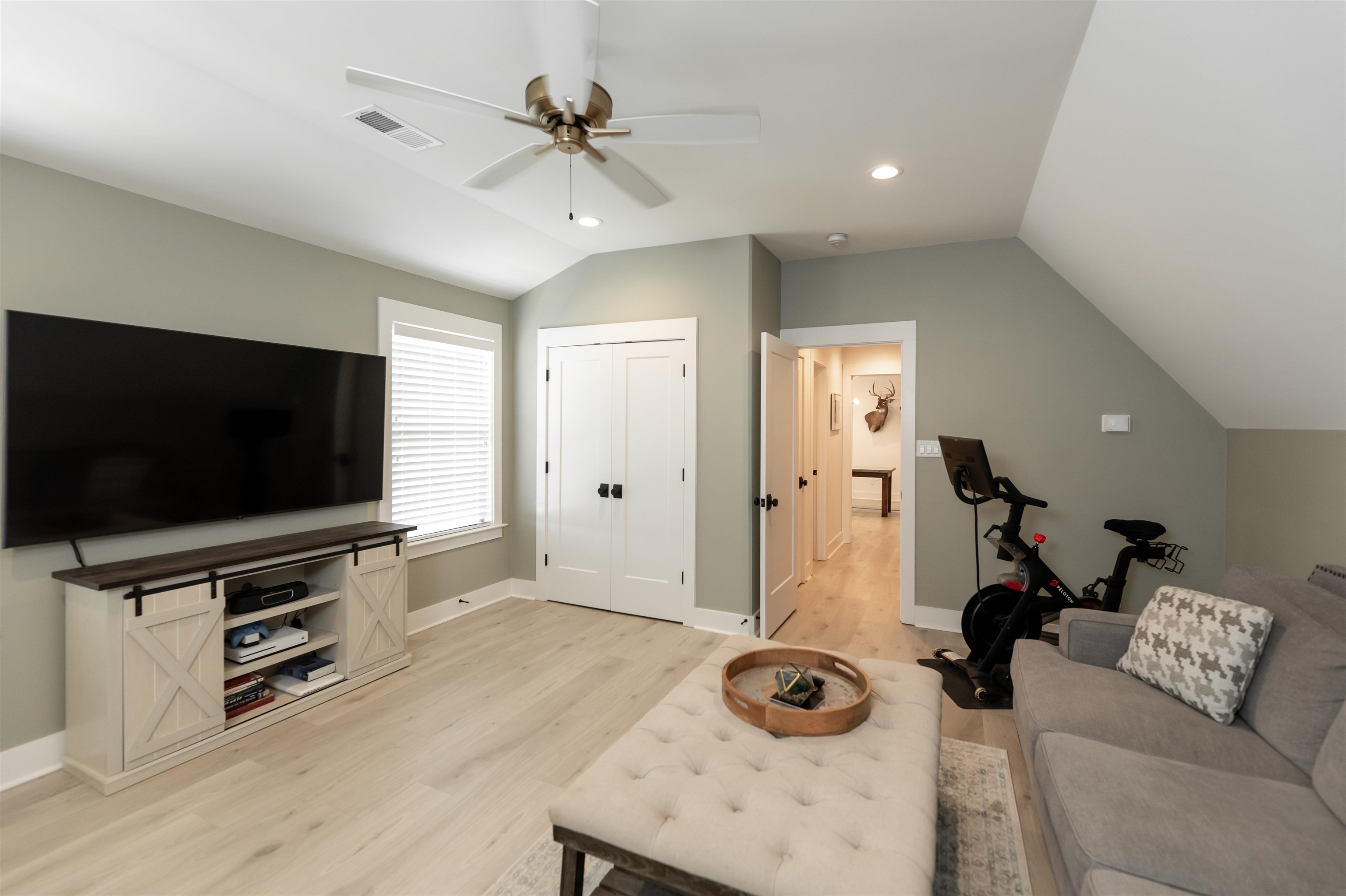 Living room featuring ceiling fan, vaulted ceiling, and light wood-type flooring