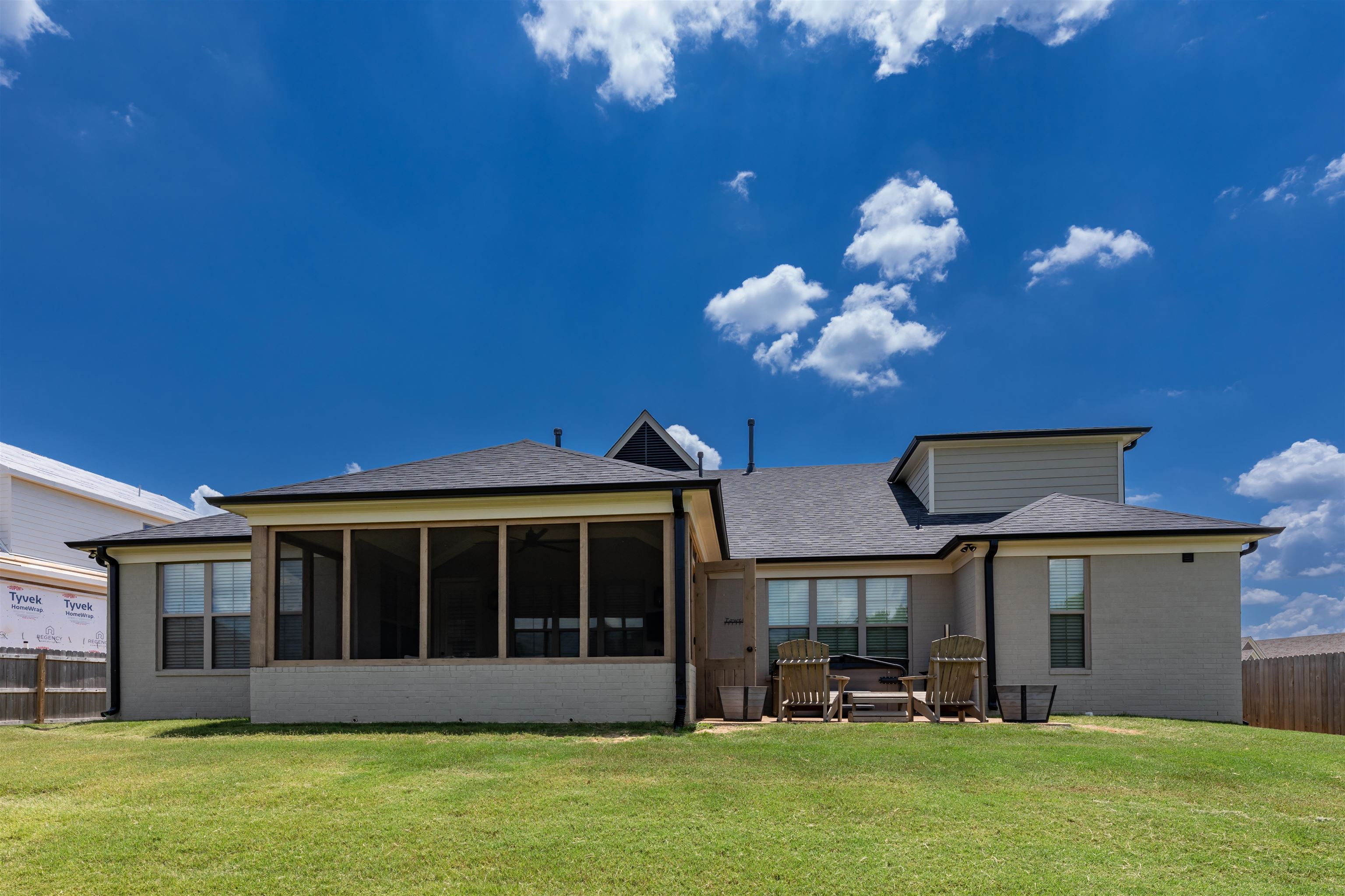 Rear view of property featuring a sunroom and a lawn