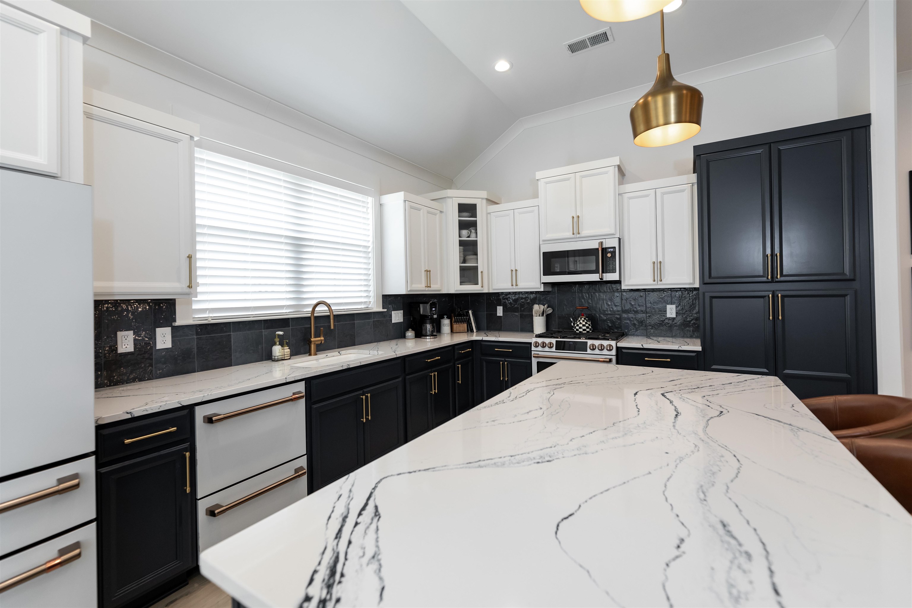 Kitchen featuring appliances with stainless steel finishes, white cabinetry, tasteful backsplash, and pendant lighting