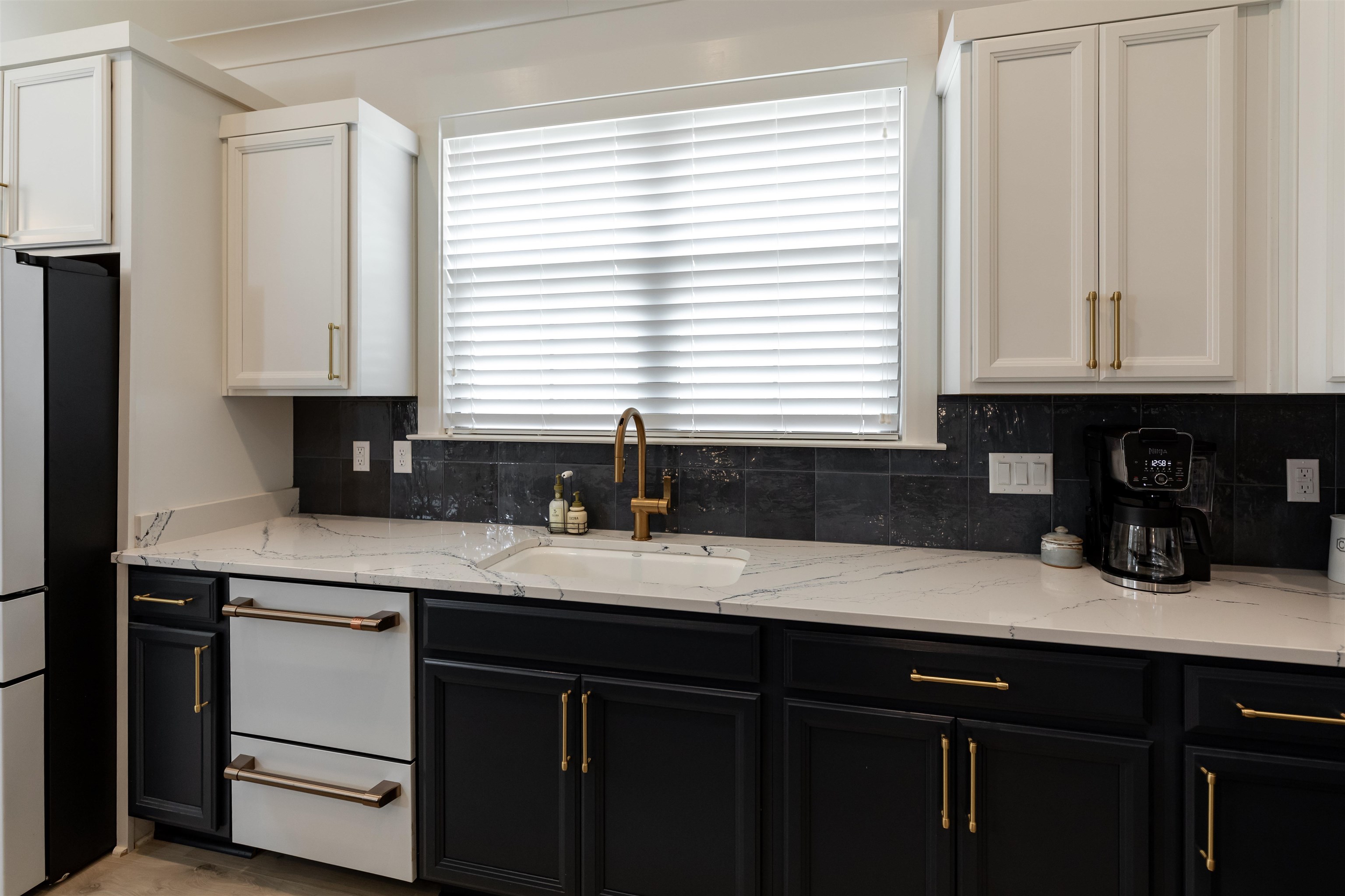 Kitchen with sink, a healthy amount of sunlight, white cabinets, and backsplash