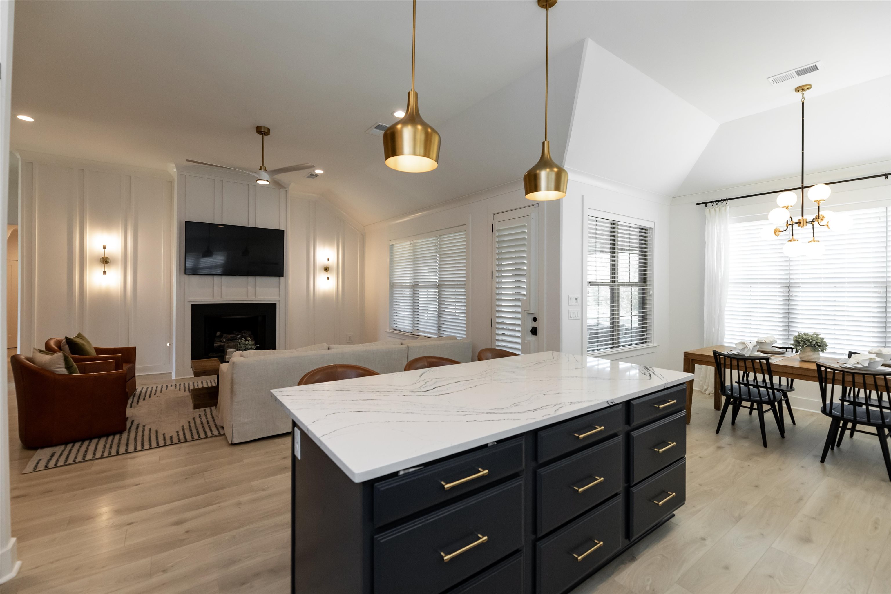 Kitchen featuring light hardwood / wood-style flooring, a fireplace, decorative light fixtures, a kitchen island, and lofted ceiling